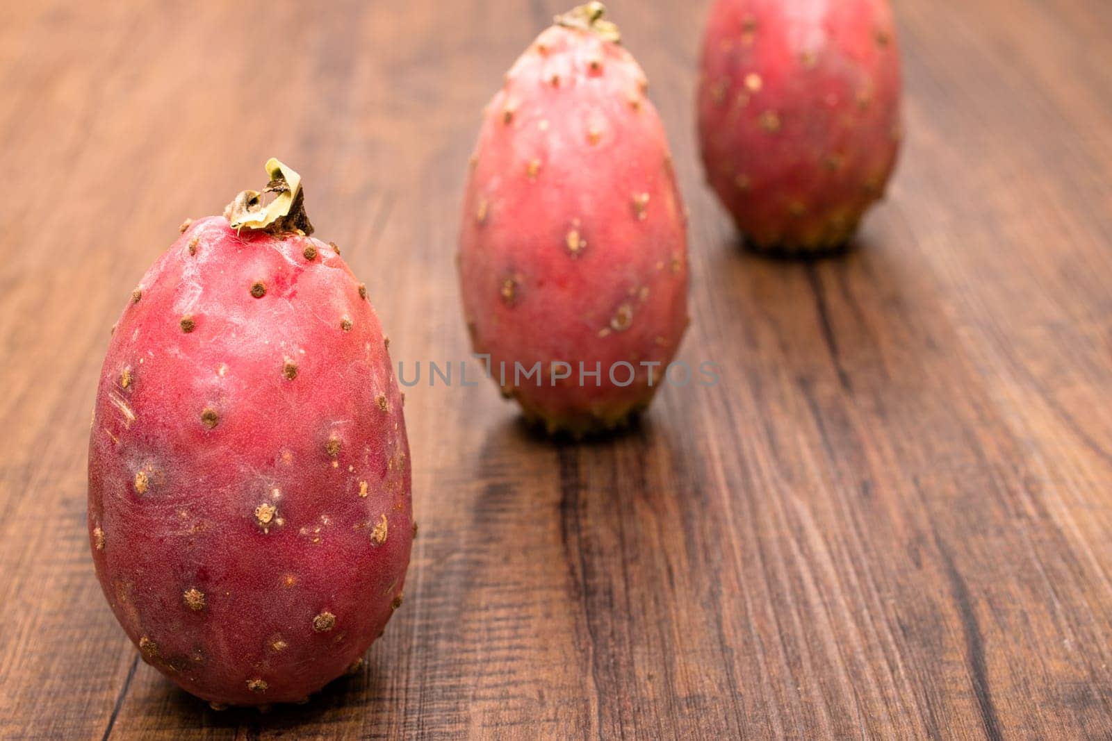 Ripe red cactus fruits on a wooden board