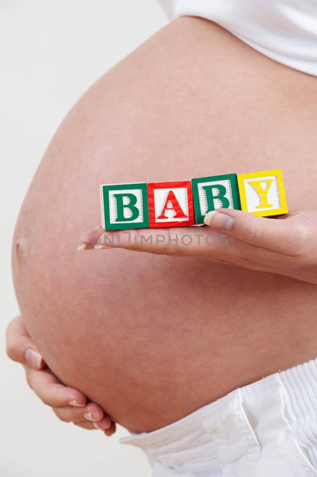Close Up Of Pregnant Woman Holding Blocks Spelling Baby