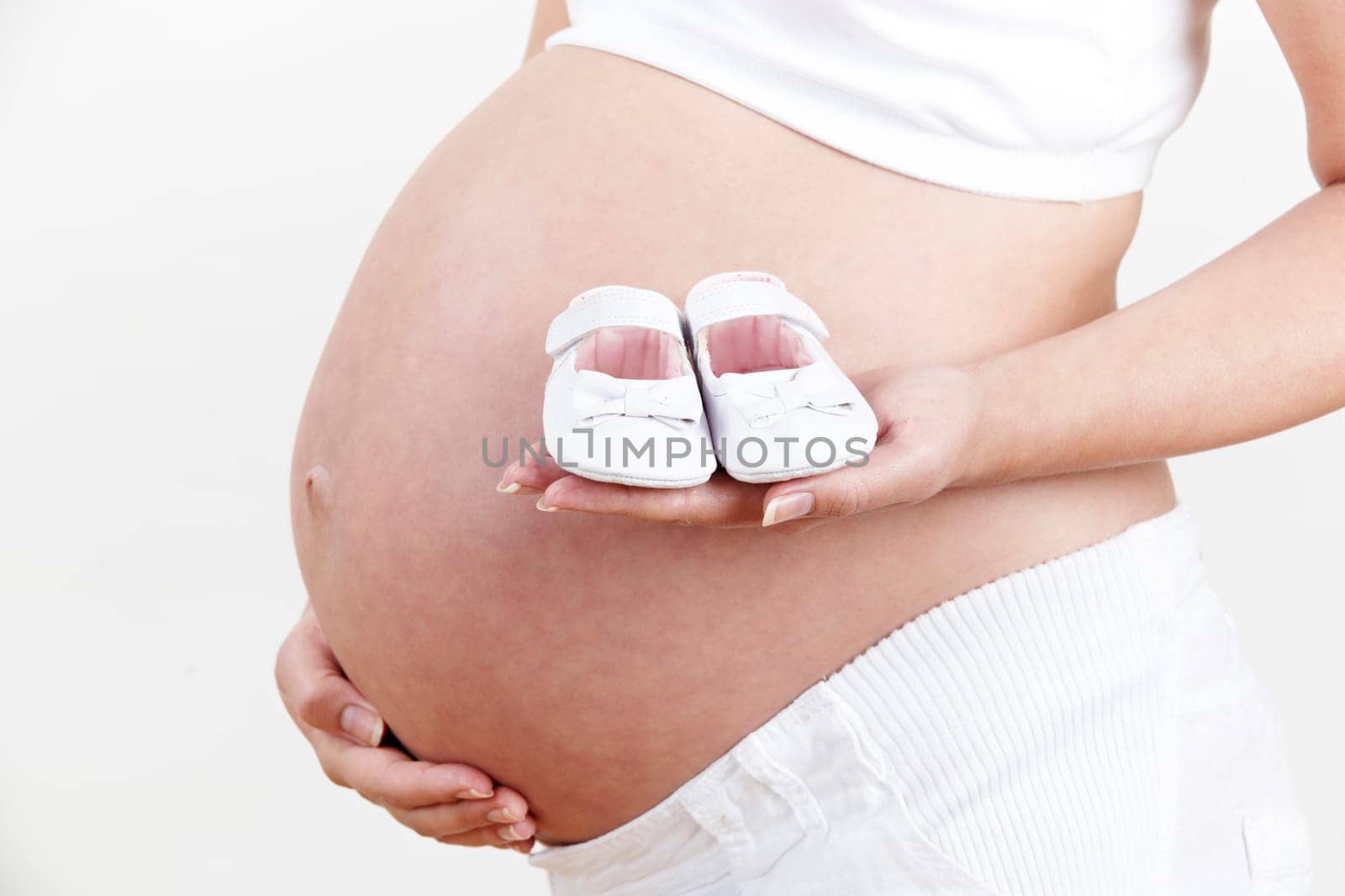 Close Up Of Pregnant Woman Holding Baby Shoes