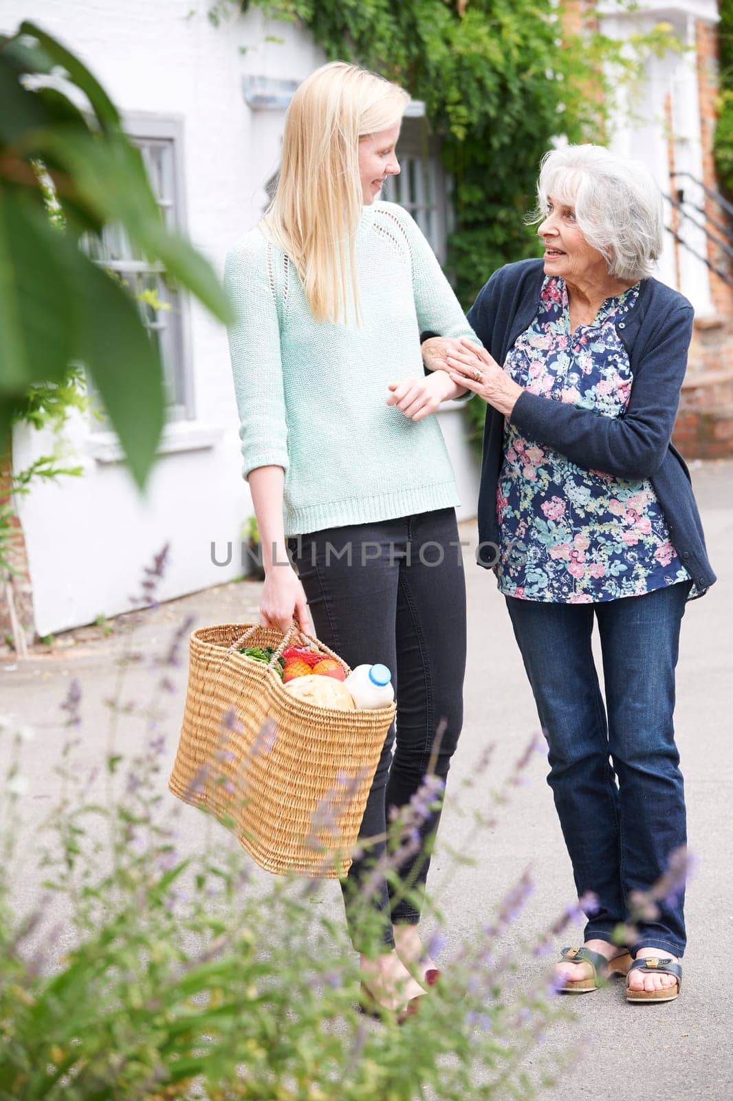 Teenage Girl Helping Senior Woman To Carry Shopping