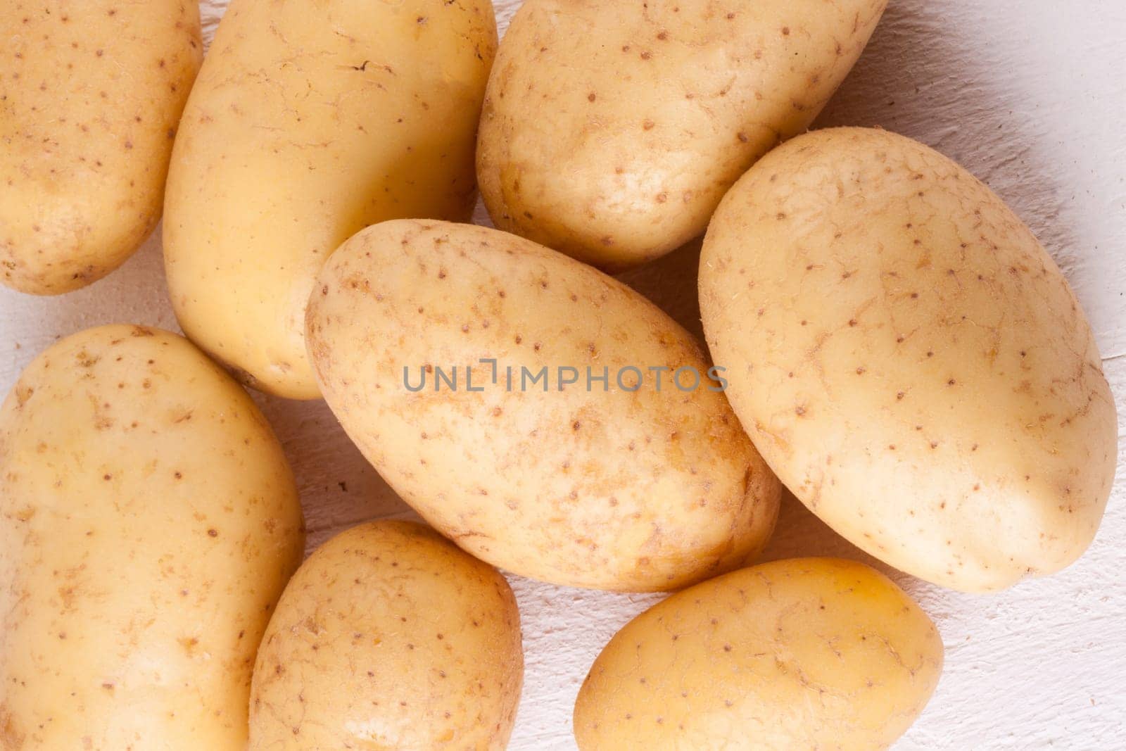 Fresh washed potatoes with peel as a close-up on a rustic wooden board