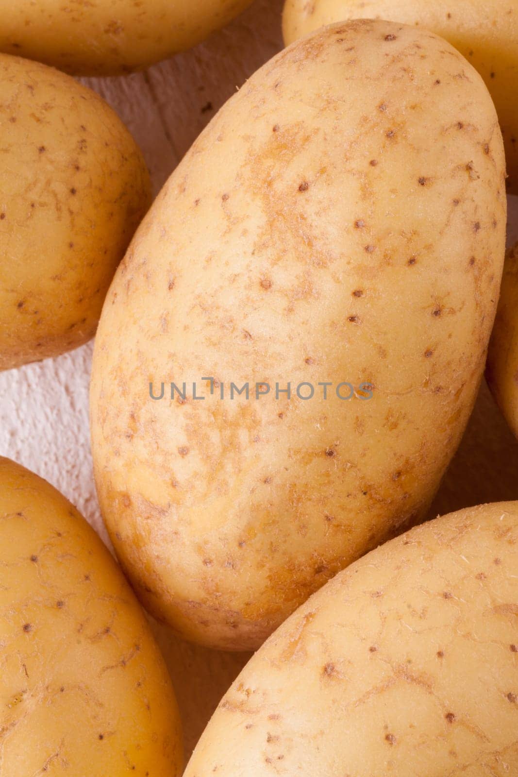 Fresh washed potatoes with peel as a close-up on a rustic wooden board