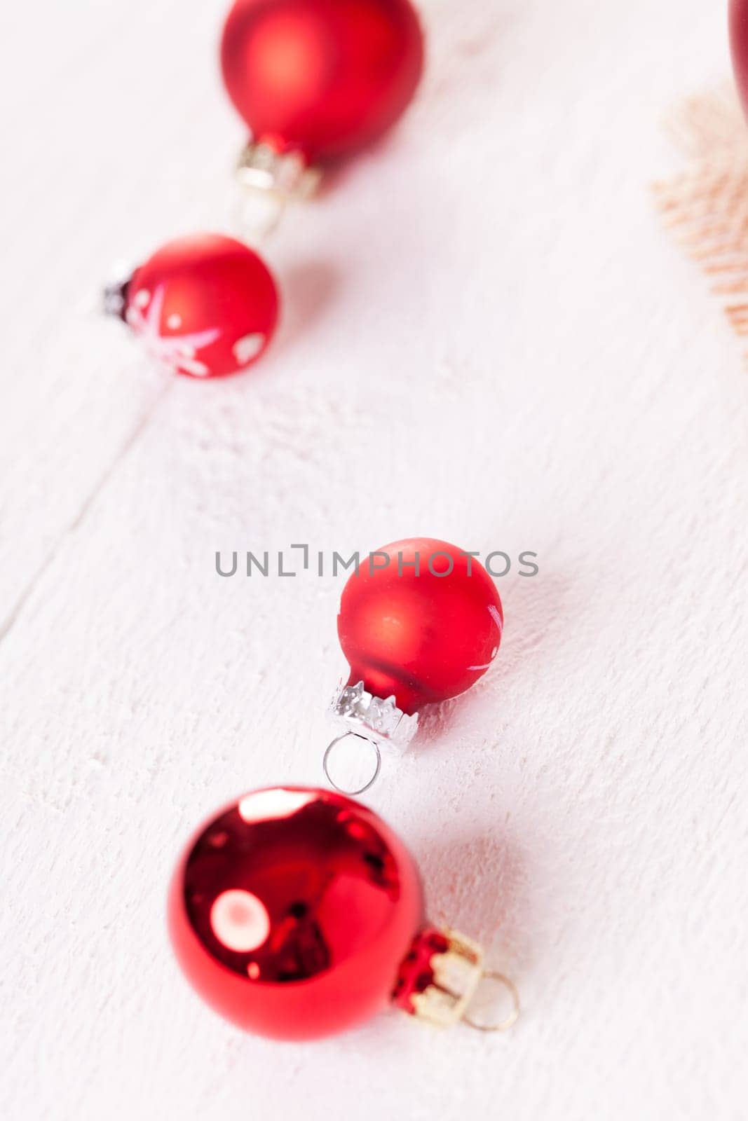 large and small red Christmas tree balls on a wooden board with a jutesack as a close-up