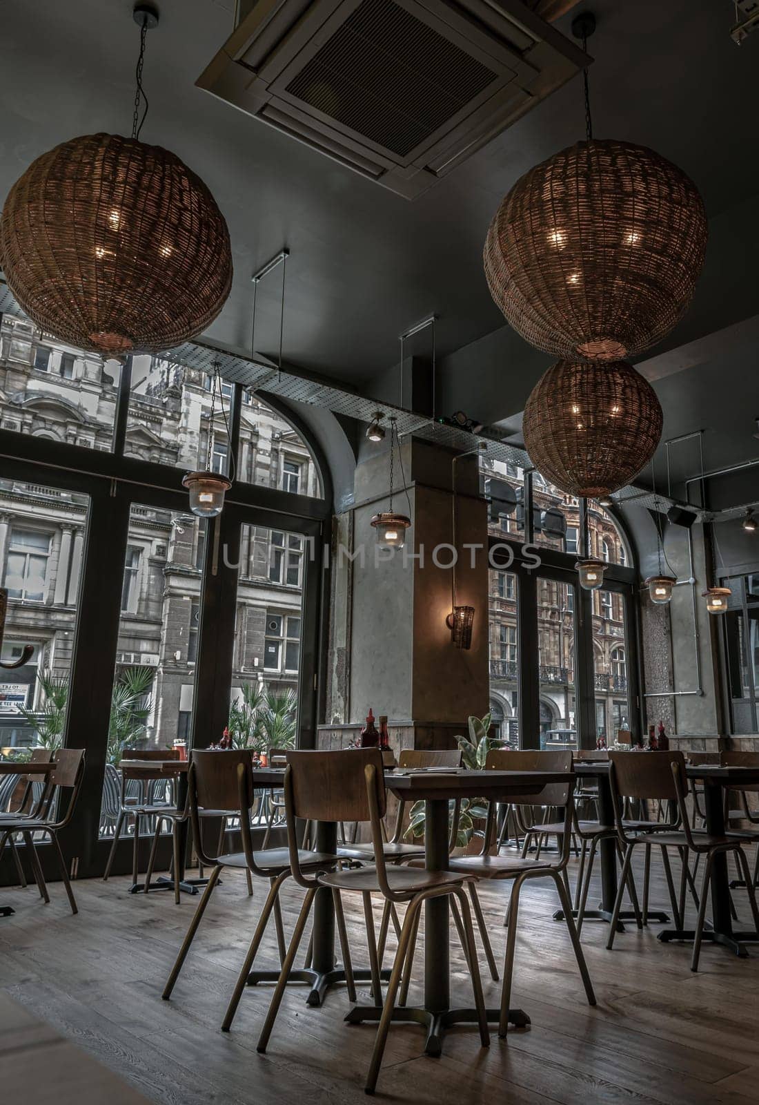 Liverpool, England - Oct 07, 2023 - Beautiful architecture design inside of Restaurant. Decorated with Glass doors, Hanging lamp made form hand-woven rattan round shape crafted ornament, Wooden dining tables and chairs. Space for text, Selective focus.