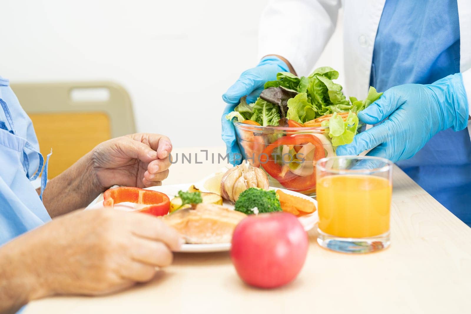 Asian senior woman patient eating Salmon steak breakfast with vegetable healthy food while sitting and hungry on bed in hospital. by pamai