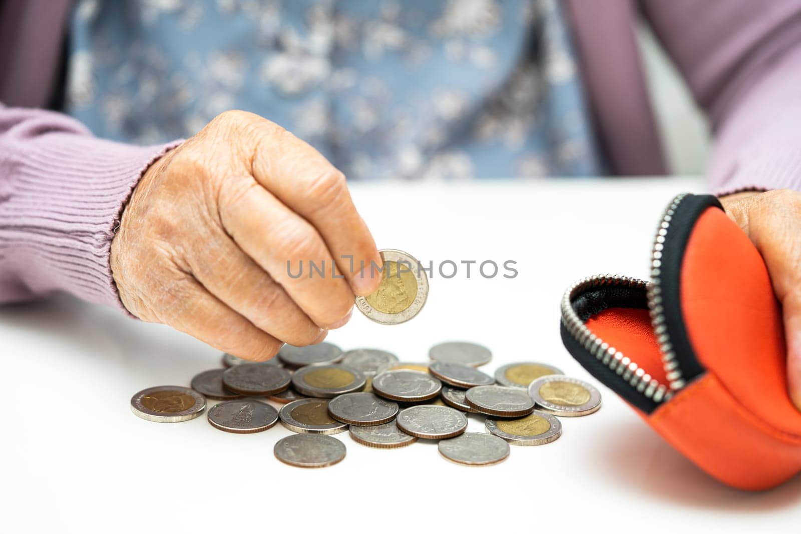 Asian senior woman holding counting coin money in purse. Poverty, saving problem in retirement. by pamai
