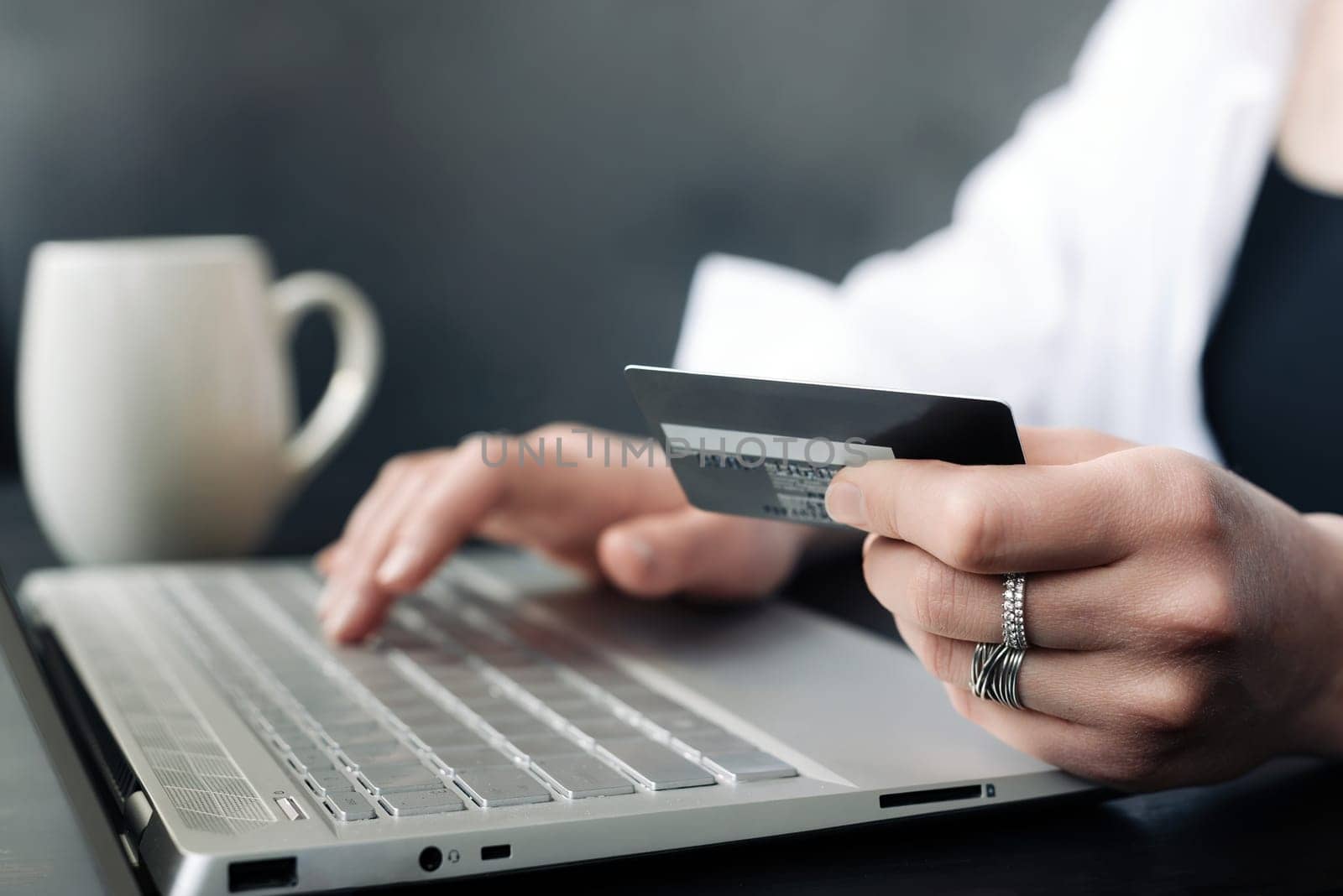 Effortless E-commerce: Woman's Hand Balancing Credit Card and Laptop. Seamless Online Shopping: Woman's Hand with Credit Card and Laptop. Digital Retail Convenience.