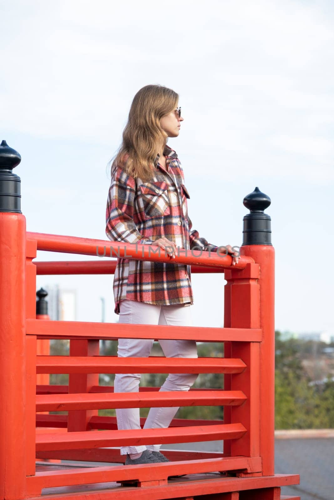 back view of unrecognizable Woman in red plaid shirt enjoying nature walking in Japanese Garden with red pagoda