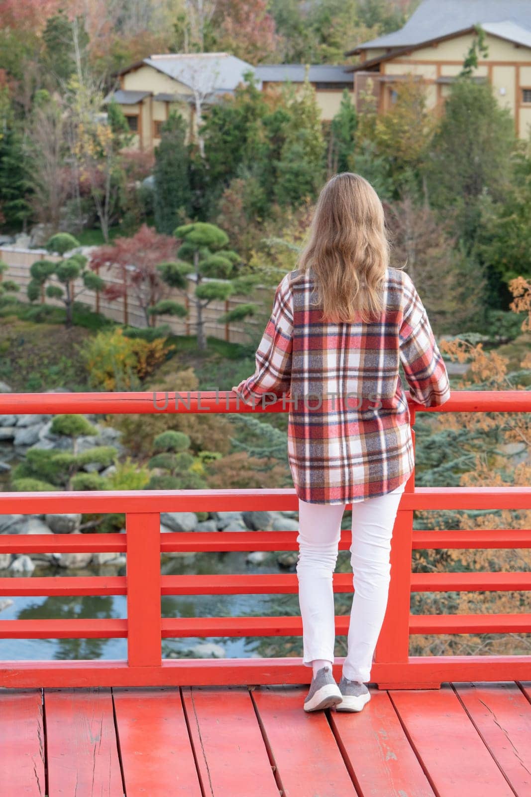 Woman in red plaid shirt enjoying nature sitting in Japanese Garden