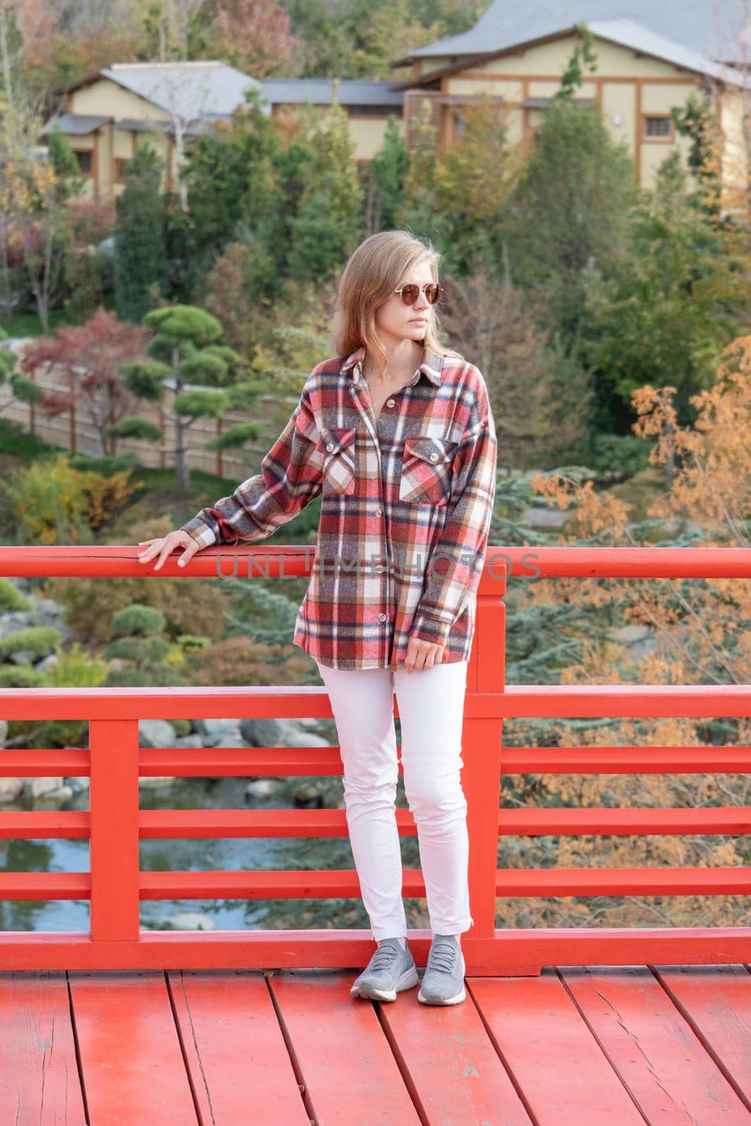 Woman in red plaid shirt enjoying nature sitting in Japanese Garden