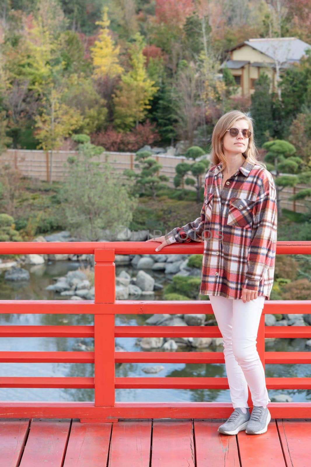 Woman in red plaid shirt enjoying nature sitting in Japanese Garden