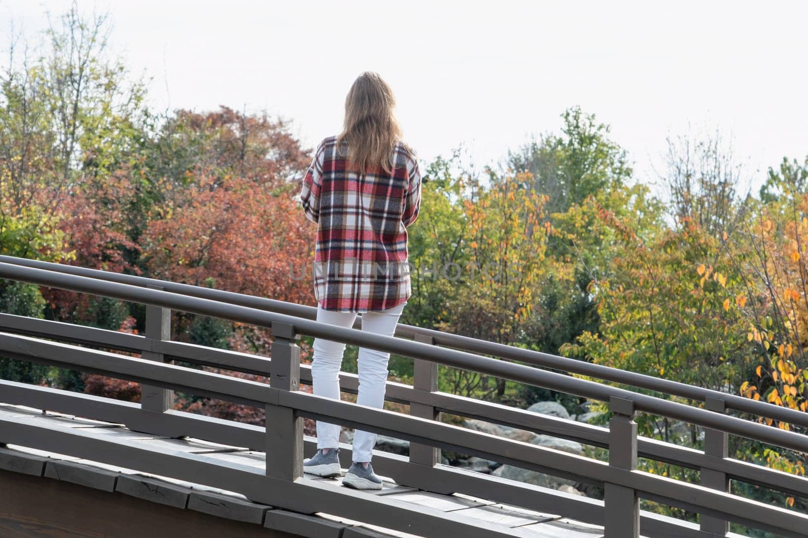 Woman in red plaid shirt enjoying nature sitting in Japanese Garden