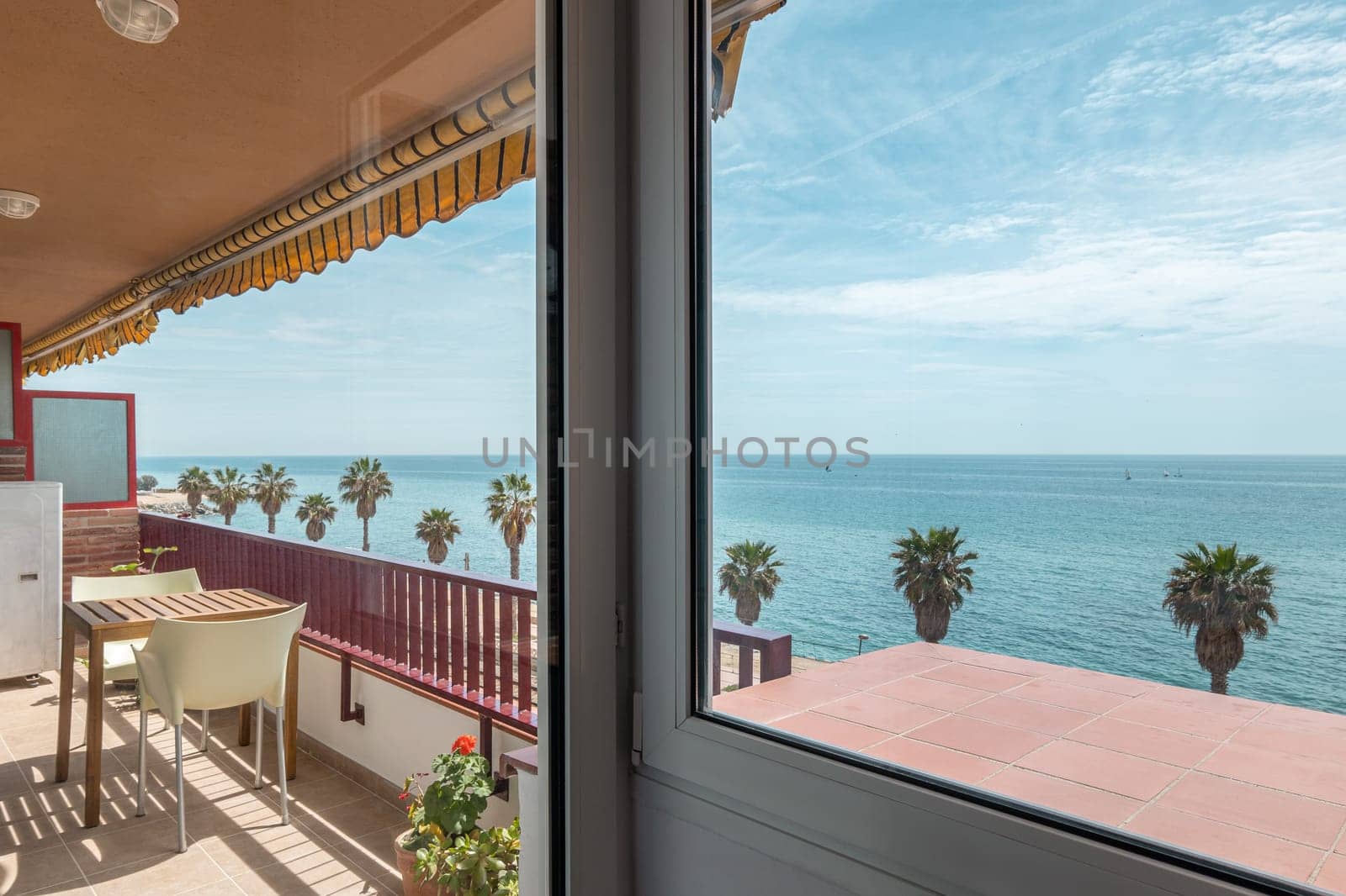 Comfortable terrace with table and seats in apartment on Vilassar de Mar embankment. Tourist flat balcony on sea coast at Catalonia resort
