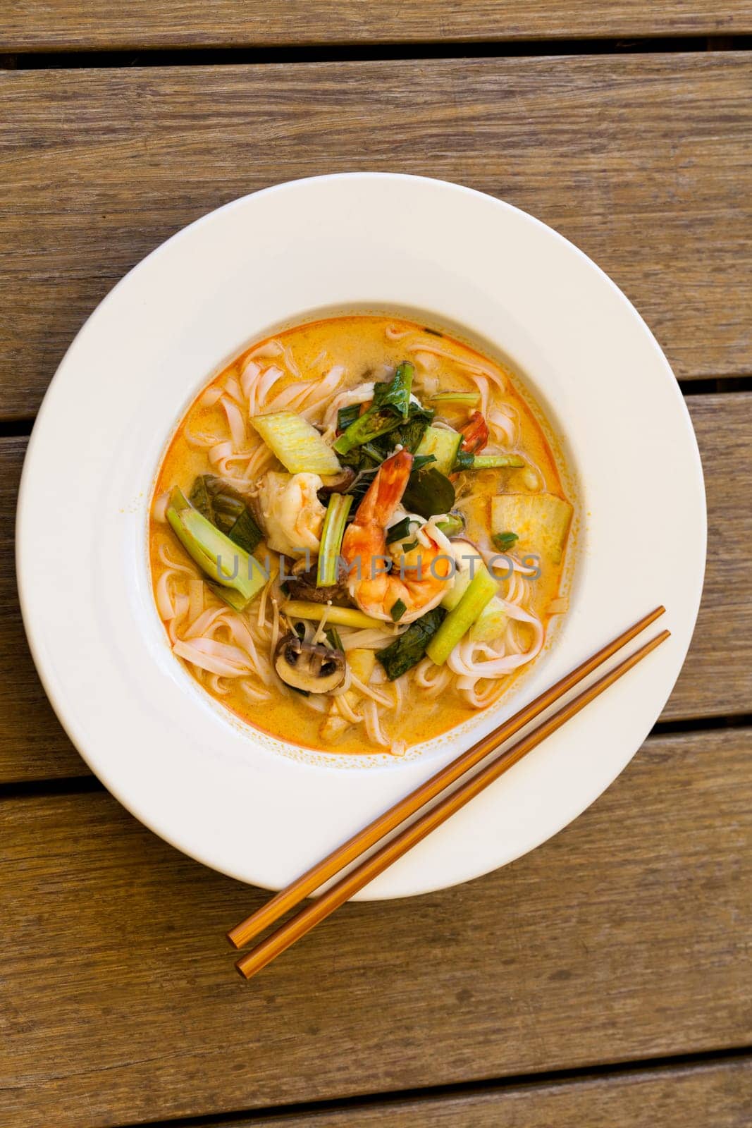 Bowl plate with freshly prepared Tom Yam soup with clanguste and coriander with chopsticks as close-up