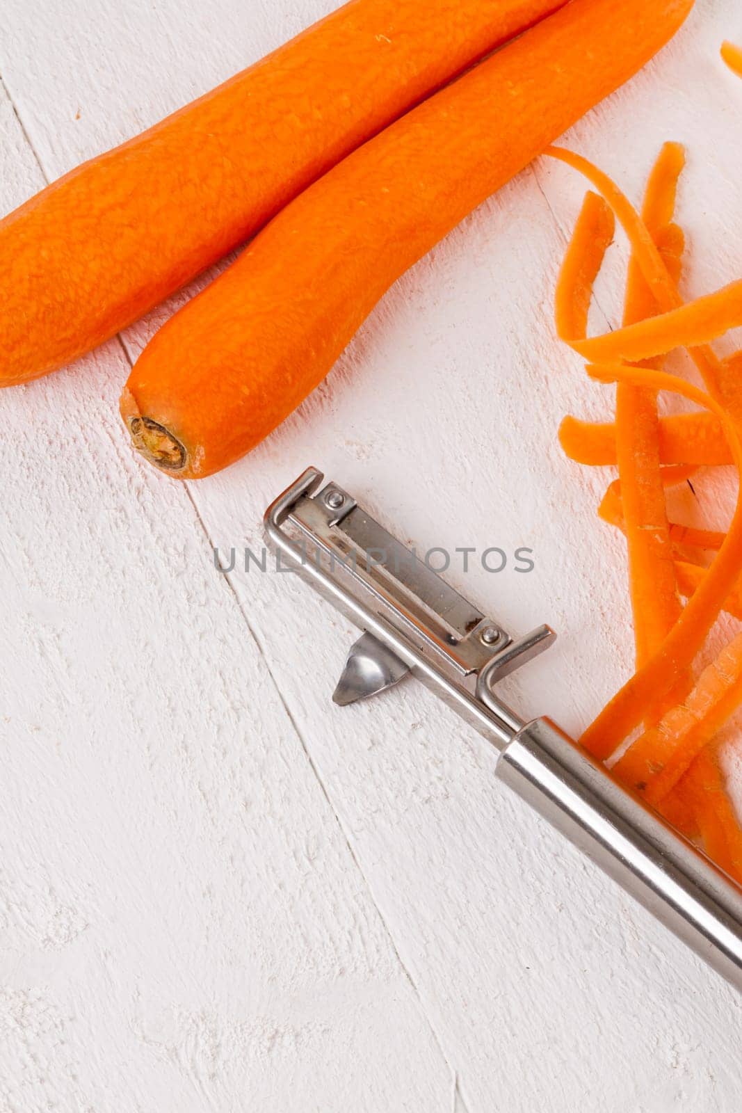 Fresh orange carrots beet turn beets peeled with peelers and bowls on a white wooden board