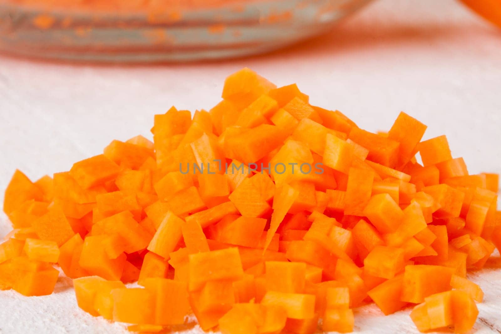 Fresh carrots beet root beet as whole and finely diced brunoise in a bowl on a white wooden board