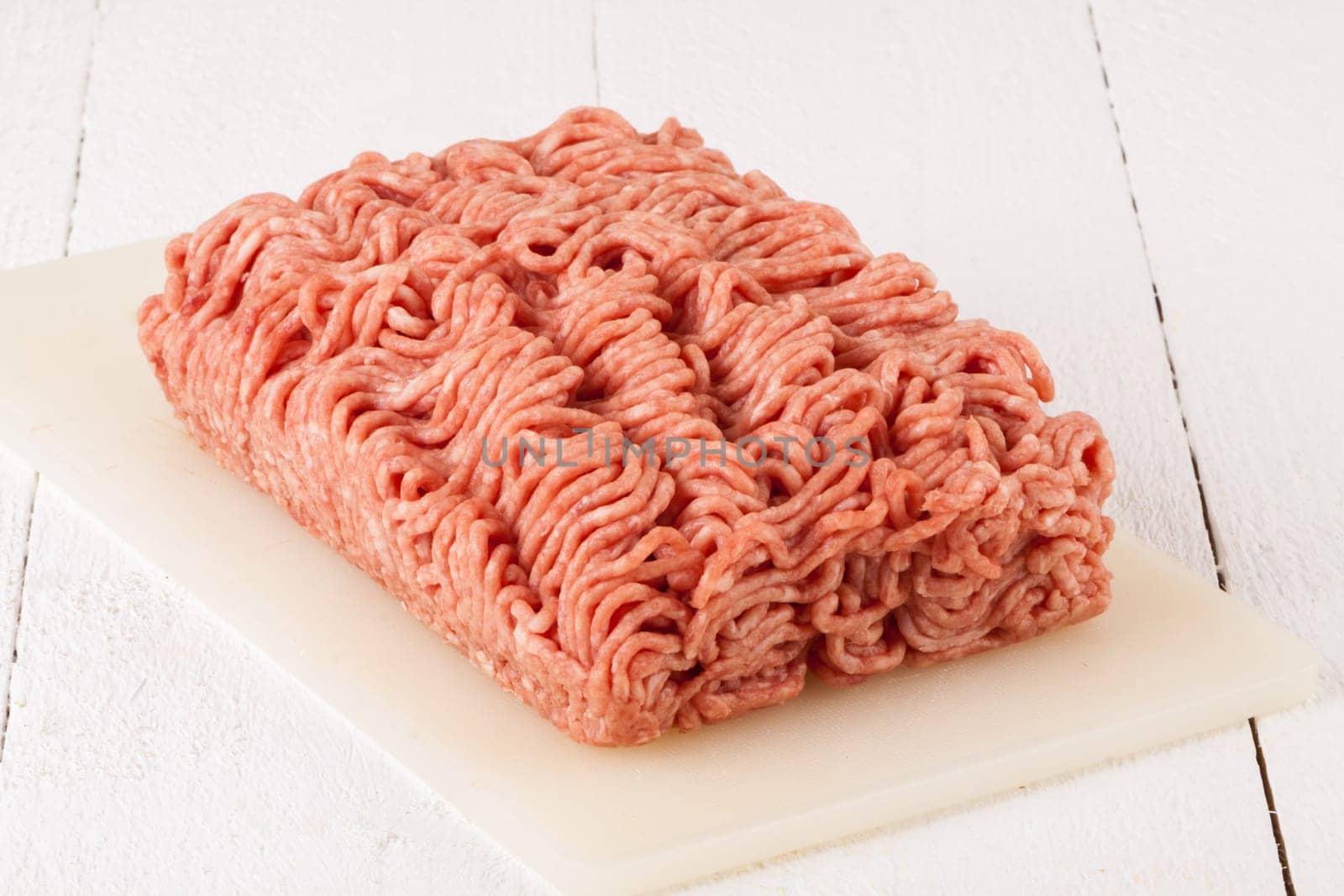Minced meat raw beef and pork mixed as a block of protective atmosphere as a close-up on a white plate