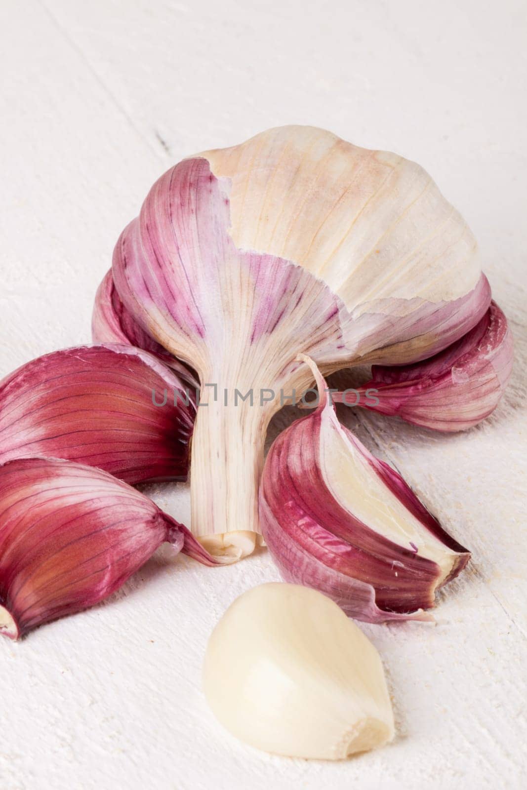 Garlic tuber with toes Fresh in whole and as a detail as a close-up on white wood