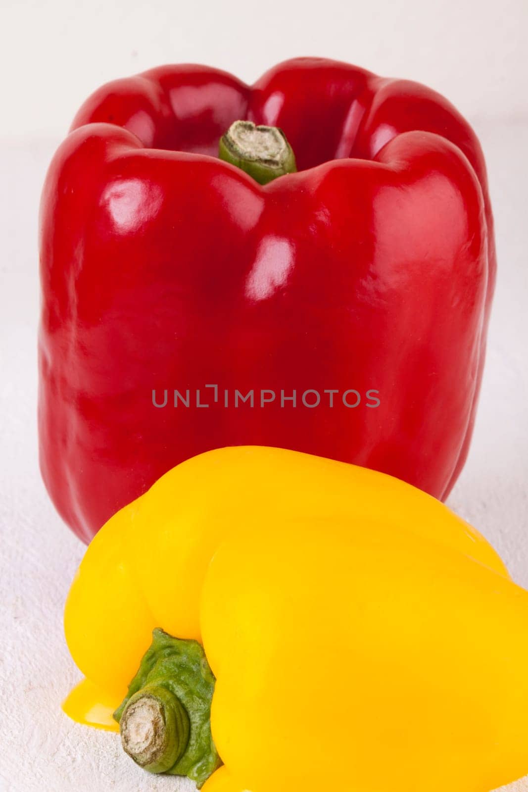 Fresh red and yellow peppers on a white wooden board as a close-up
