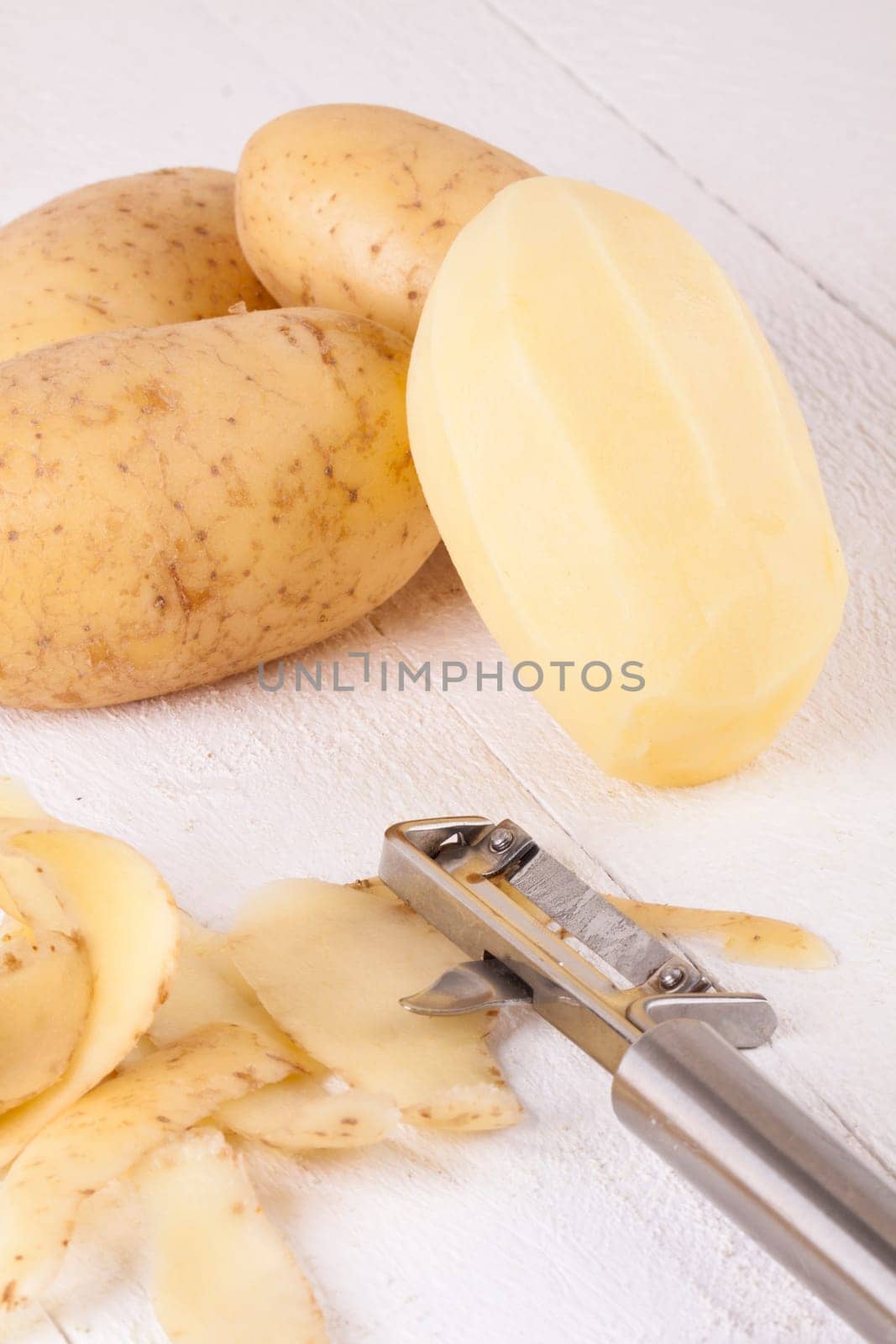 Potatoes with peels and peeled with potato peeler Peeler as close-up