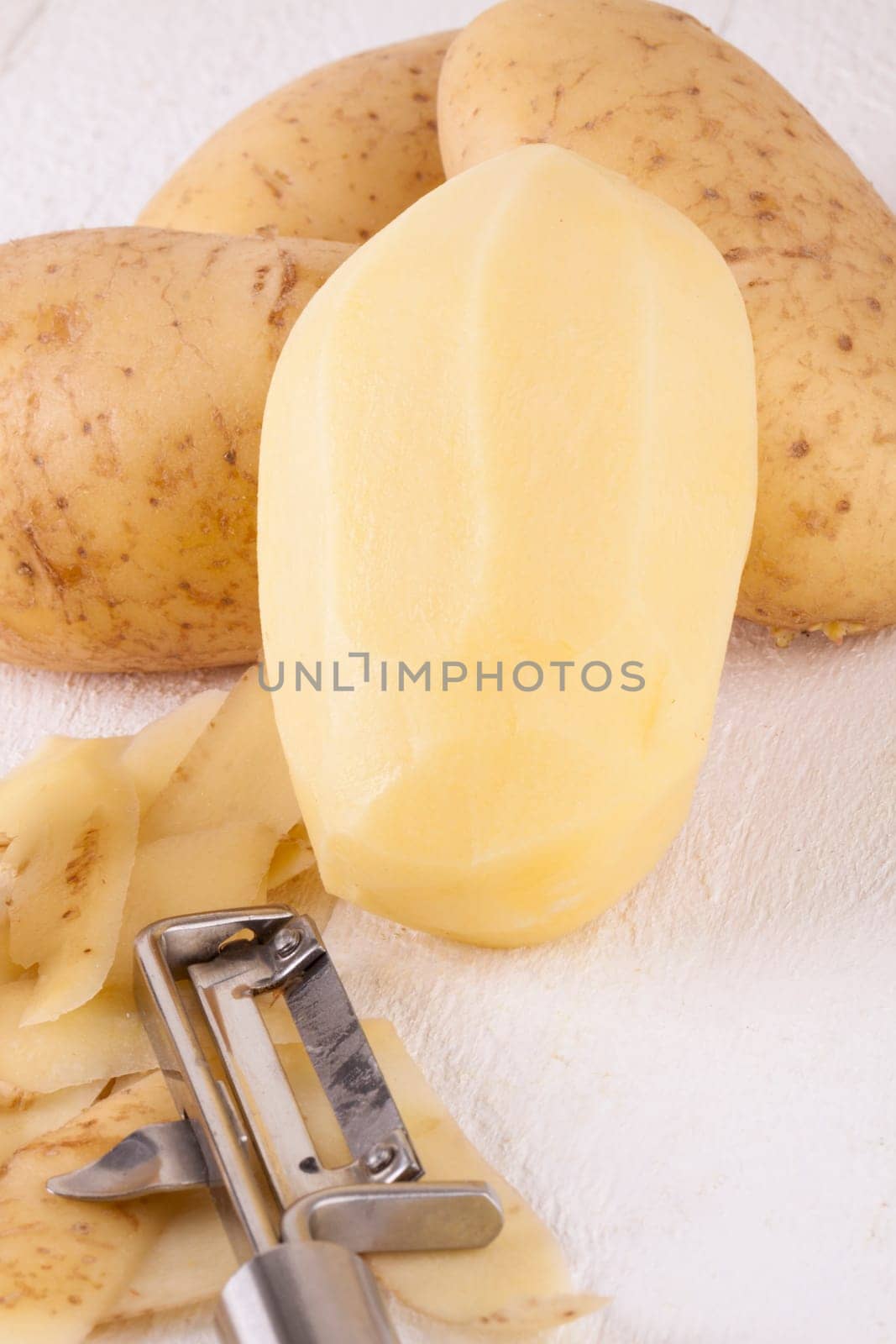 Potatoes with peels and peeled with potato peeler Peeler as close-up