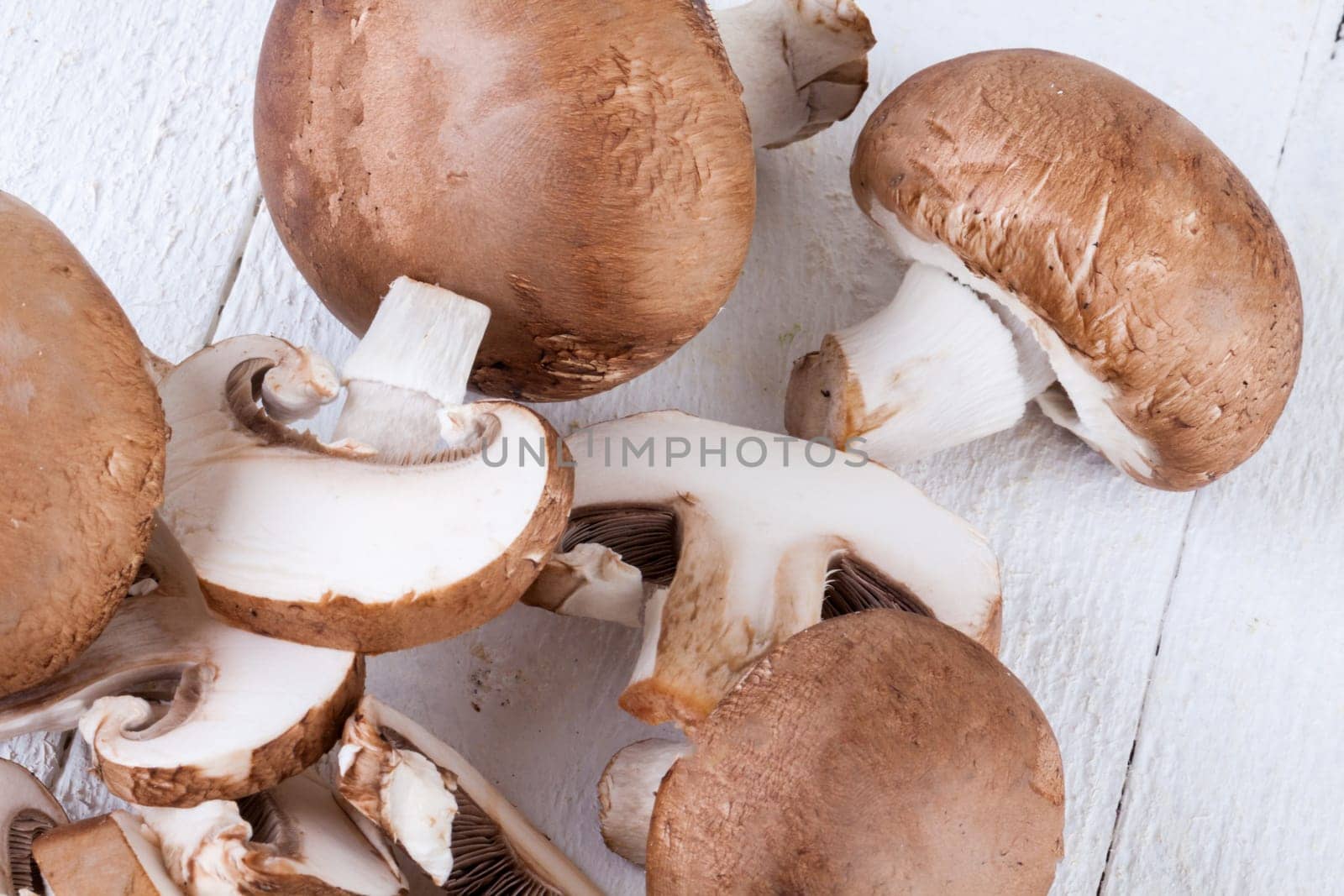 Fresh stone mushrooms Champiggnons whole and sliced on a white wooden board
