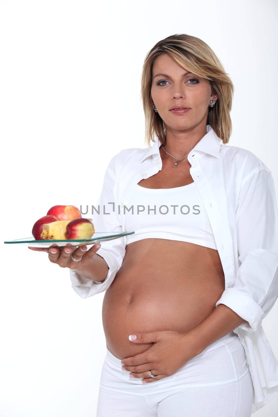 Pregnant woman holding a plate of apples