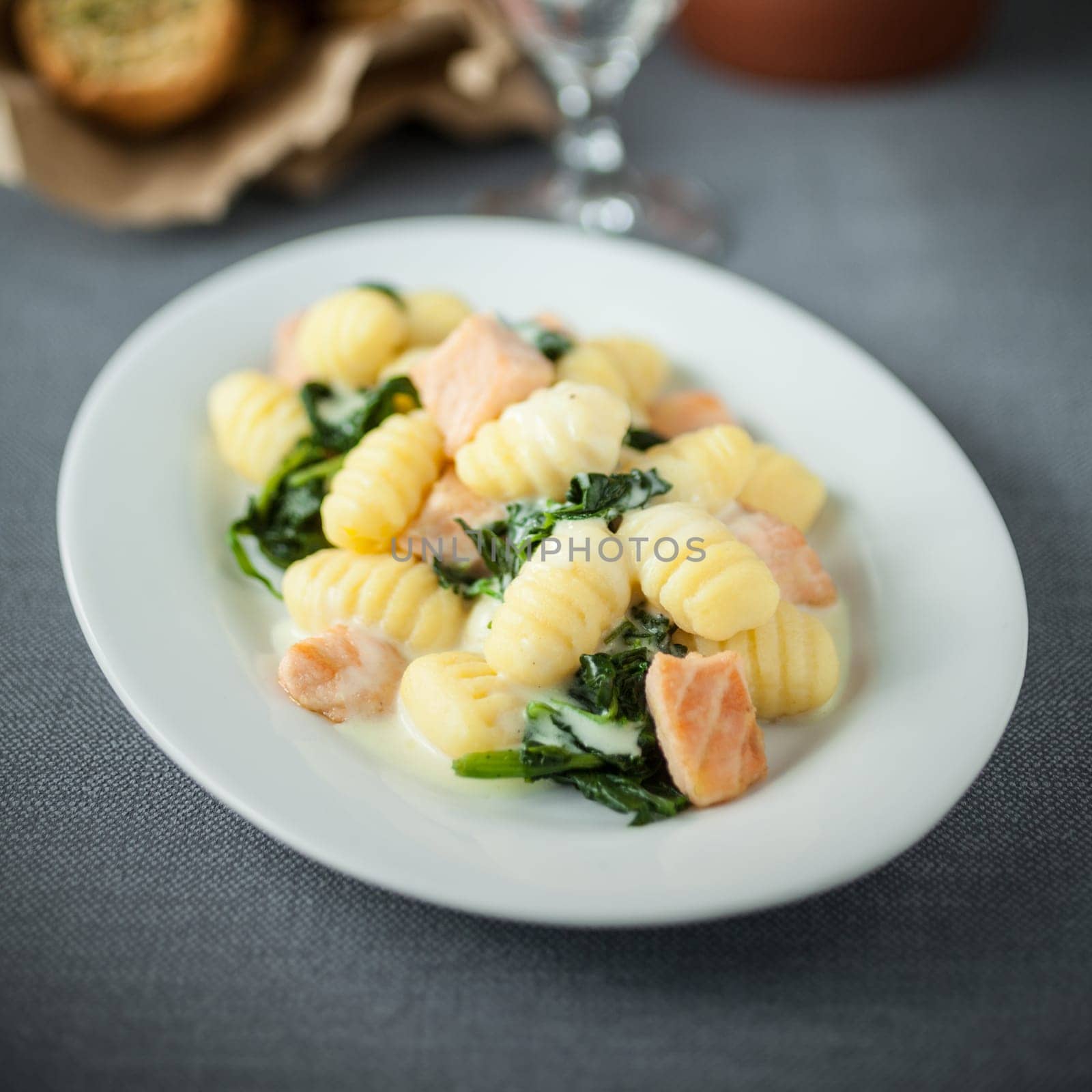 Salmon served with sauteed Italian gnocchi pasta and basil on an oval platter for delicious Mediterranean cuisine