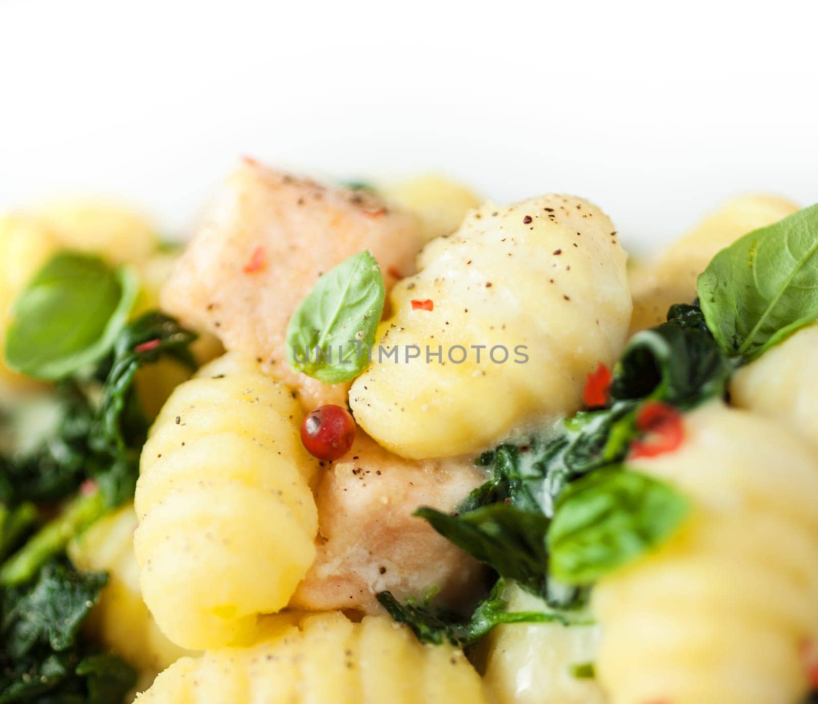 Italian gnocchi pasta, or dumplings made from semolina, with basil and salmon , closeup view seasoned with spices