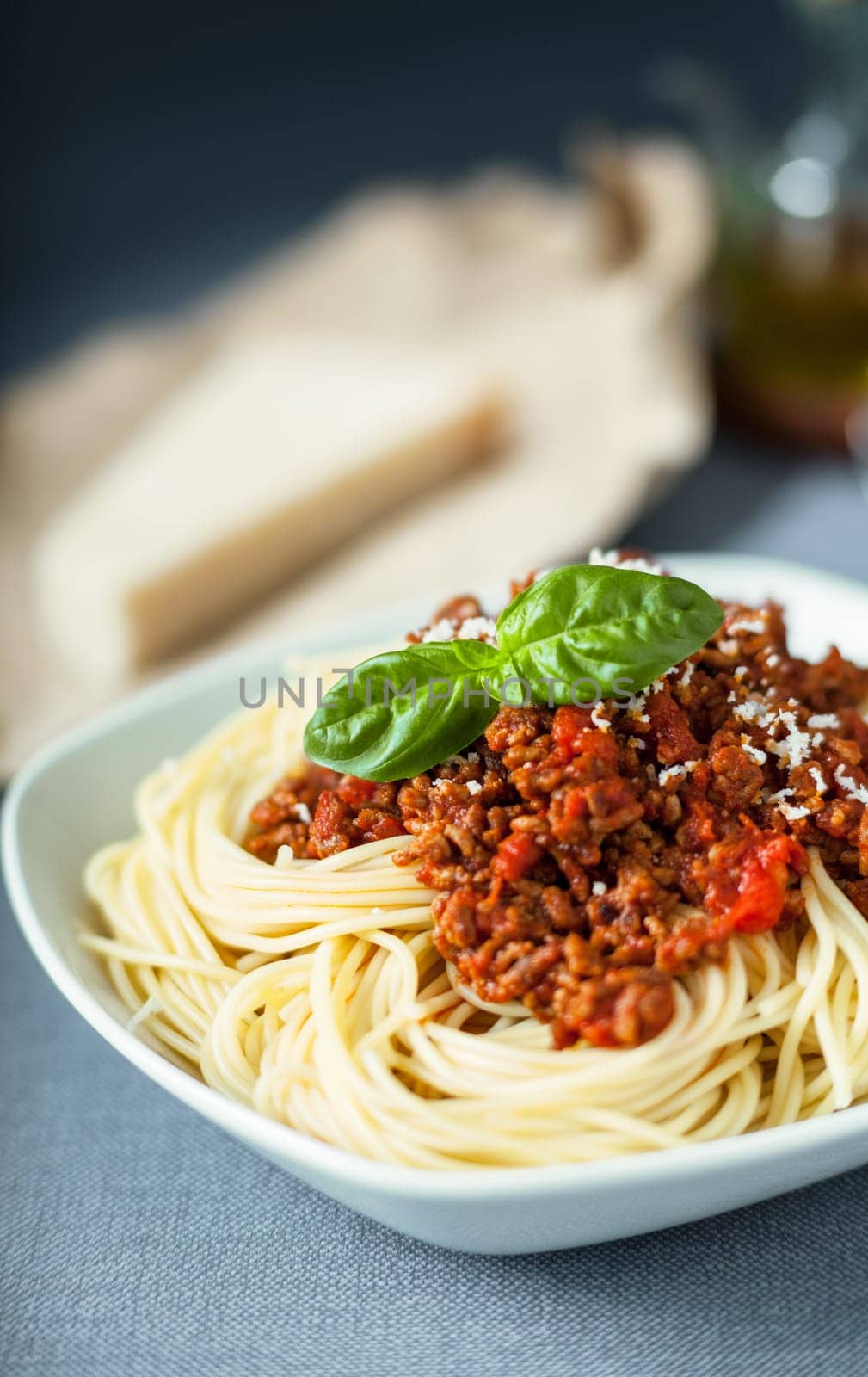 Traditional Italian spaghetti Bolognese topped with grated with parmesan cheese sprinkled on a tomato based meat sauce garnished with basil leaves