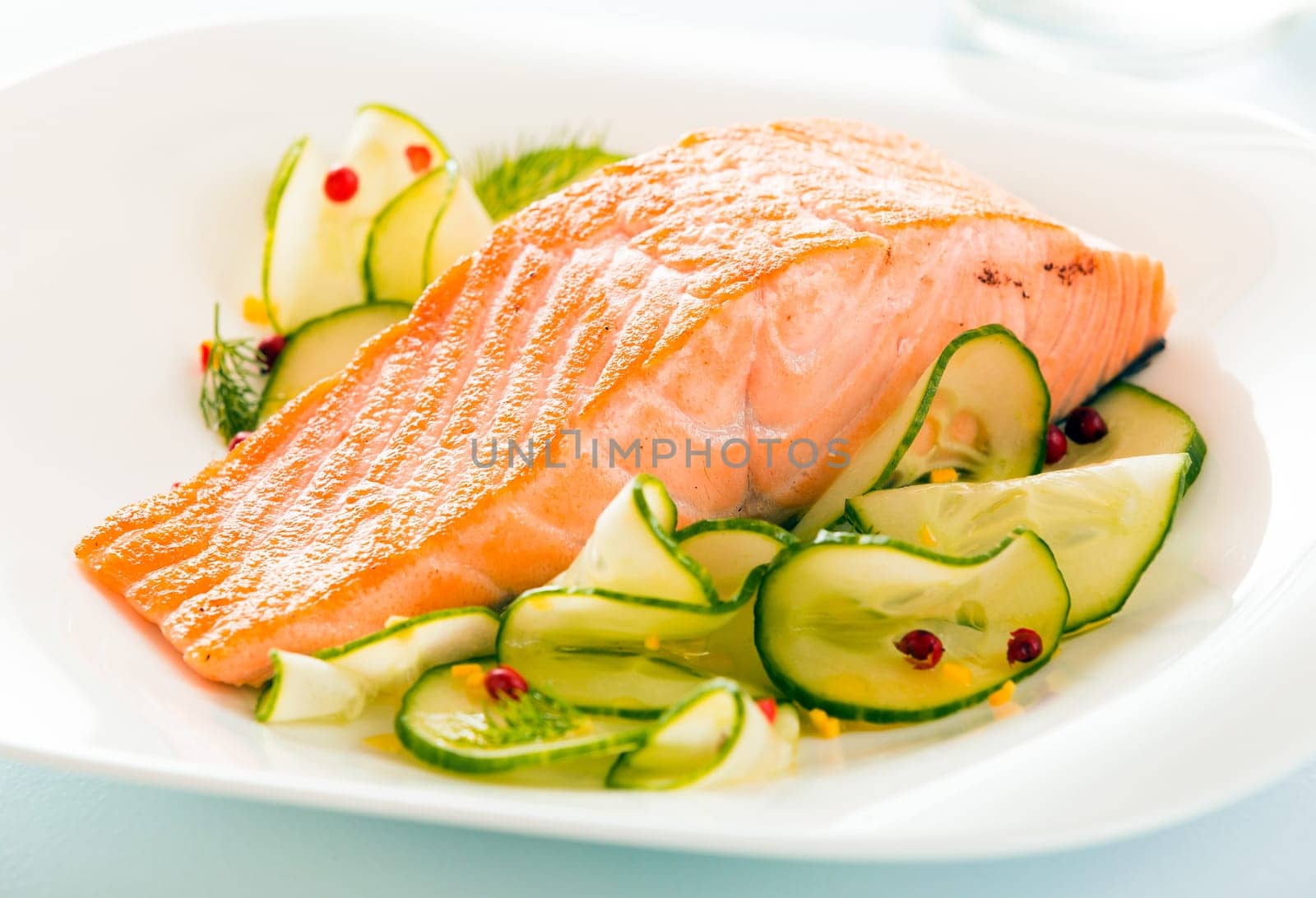 Gourmet oven-baked pink salmon steak served with thinly sliced cucumber as a delicious seafood starter to a dinner