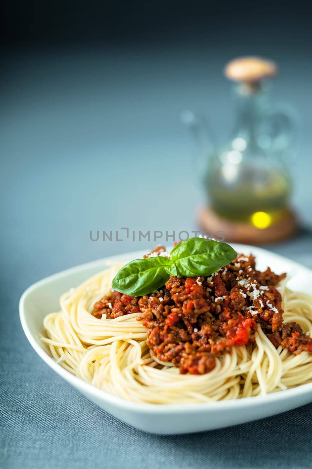 Italian spaghetti Bolognaise with a delcious tomato based meat sauce on spaghetti noodles topped with grated parmesan and fresh basil and served with olive oil