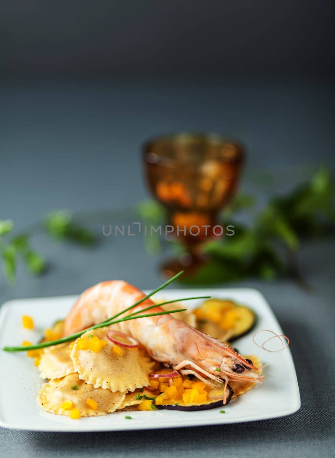Italian ravioli and shrimp starter with roasted aubergine or eggplant and fresh chives for delcious Mediterranean cuisine