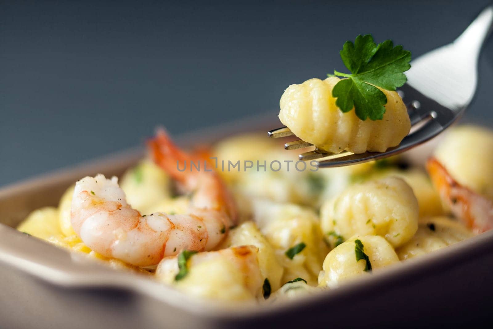 Italian gnocchi pasta, or dumplings made with semolina, with prawns or shrimps for a delicious seafood cuisine with one dumpling on a fork with selective focus