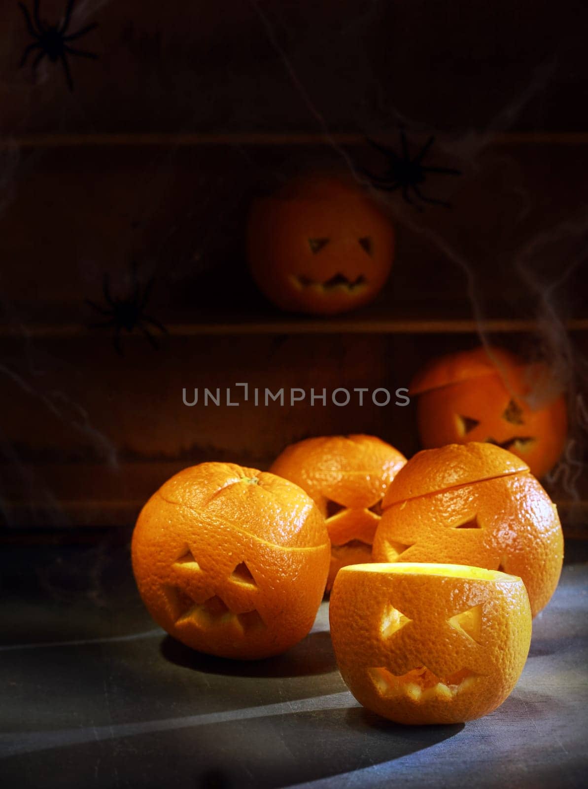 Group of Six Jack o Lanterns Carved from Oranges with Shelves in Background