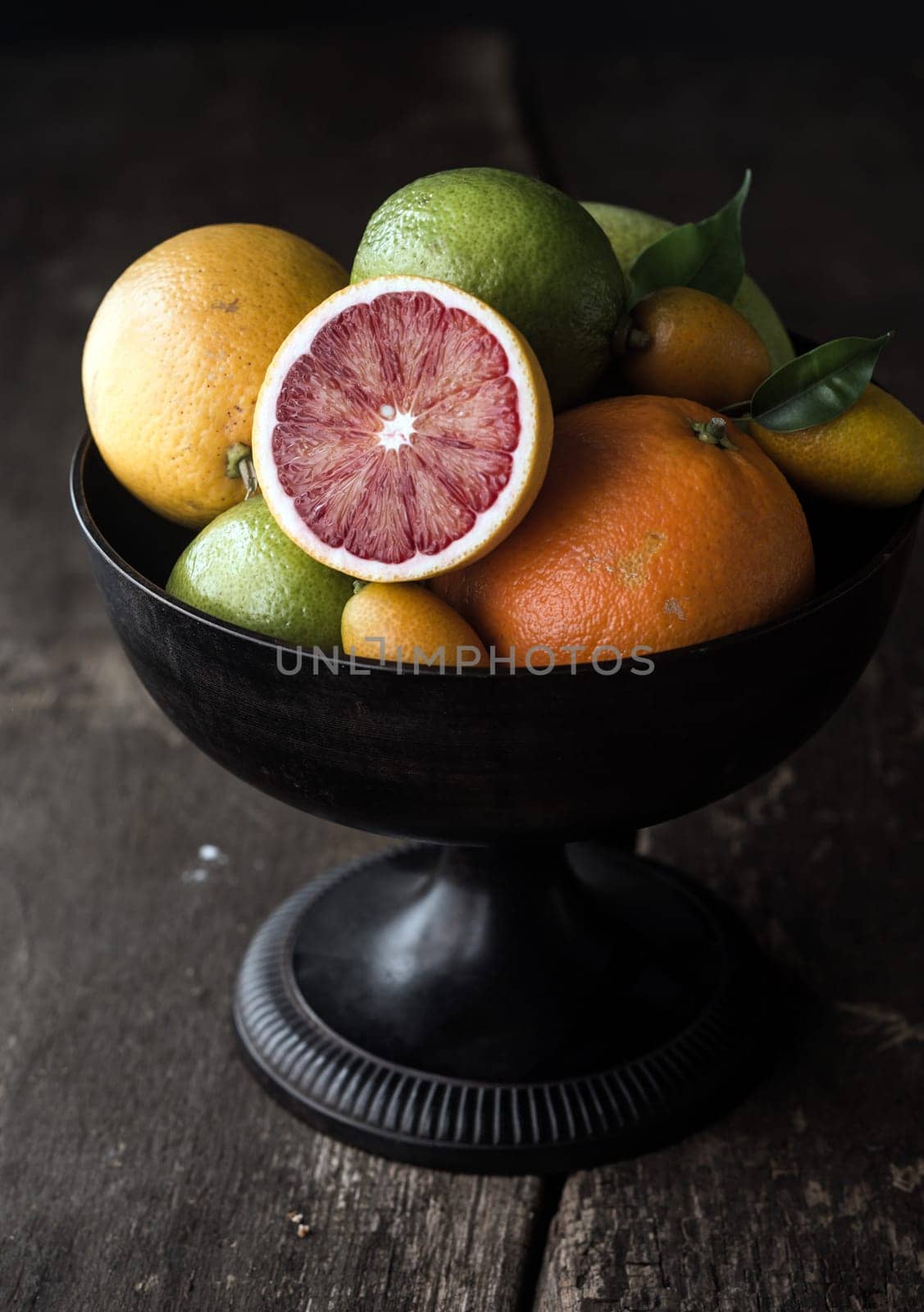 Delicious halved blood orange showing the red pulp on a citrus fruit display in a fruit bowl on an old rustic wooden table