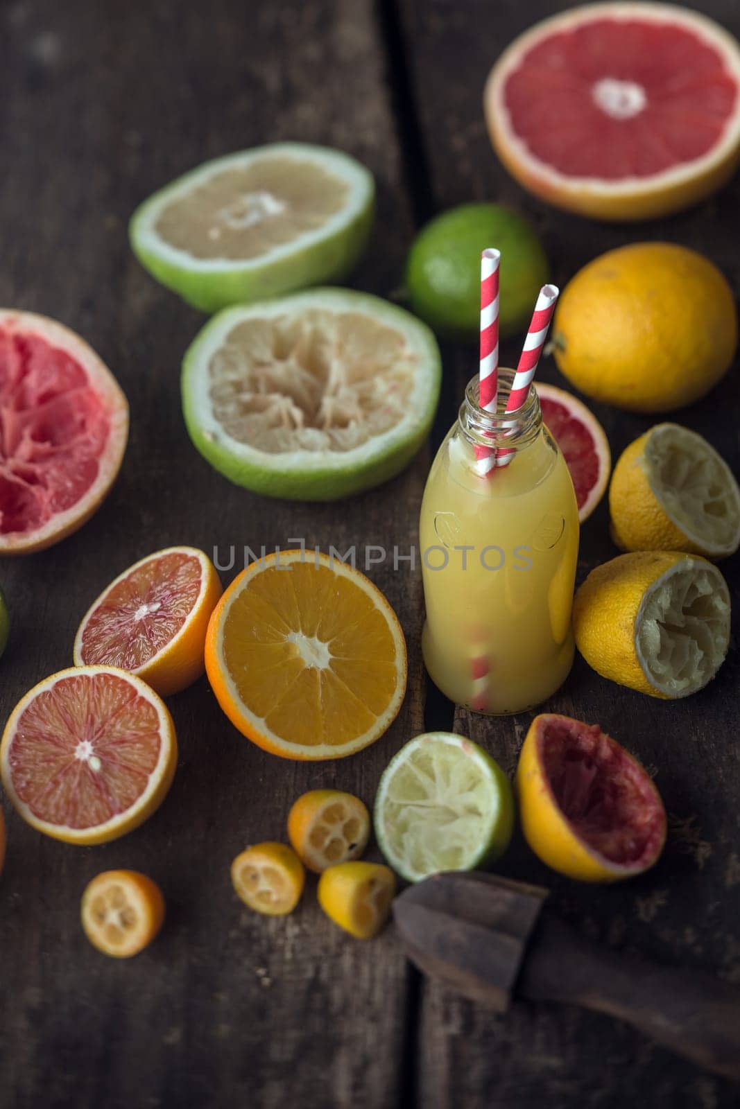 Preparing fresh grapefruit and lemon juice in a country kitchen with a freshly squeezed bottle of juice surrounded by halved grapefruit, lemons, oranges and limes