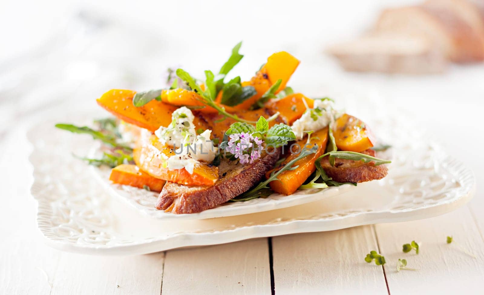Gourmet Pumpkin Salad with Roasted Hokkaido and Grilled Bread. Served on White Wooden Table.