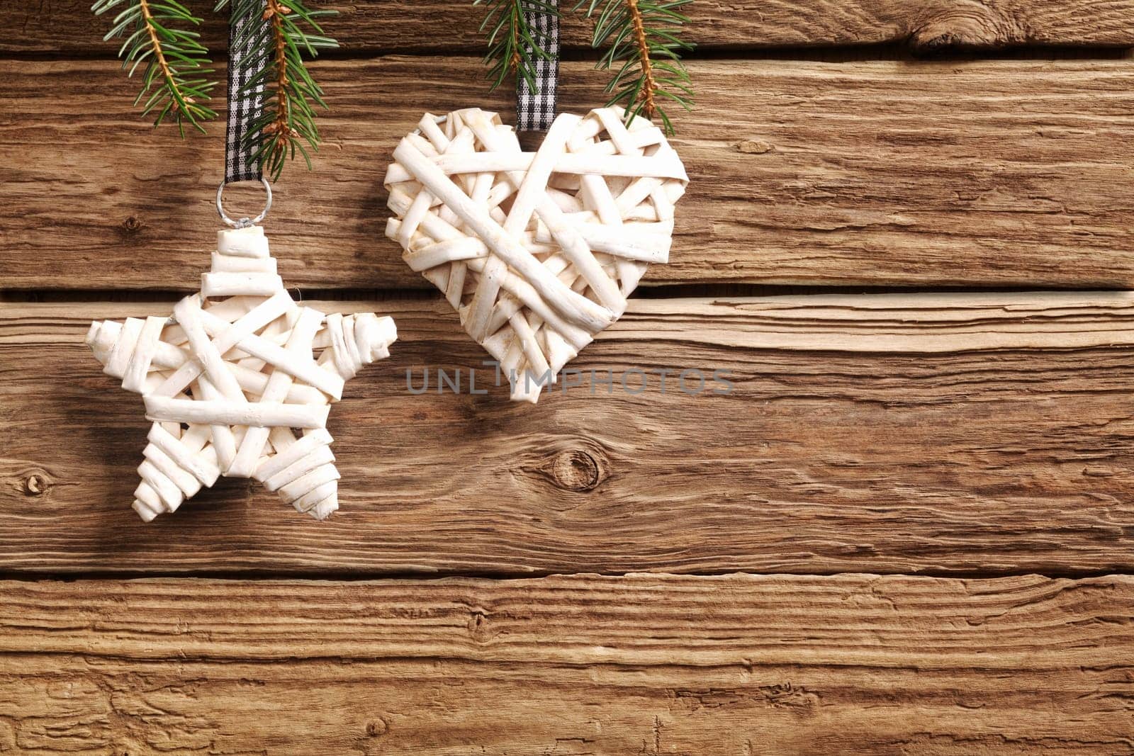 Two rustic straw Christmas ornaments on a textured wooden background with copyspace with a symbolic star and heart for a seasonal greeting for loved one