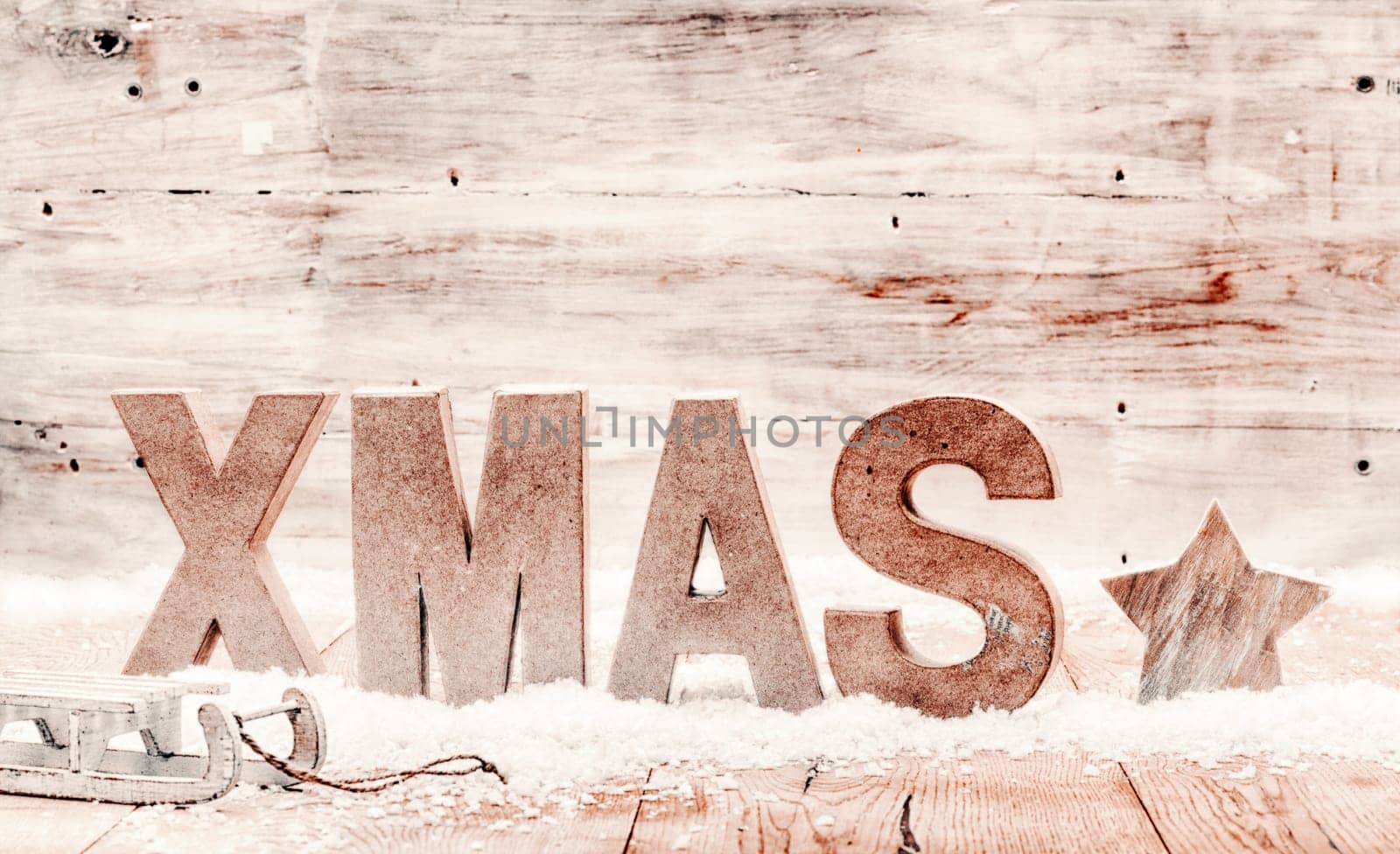 Simple country Xmas background composed of wooden handicrafts in winter snow with the letters - Xmas - a star and childs toboggan on weathered wood background with copyspace