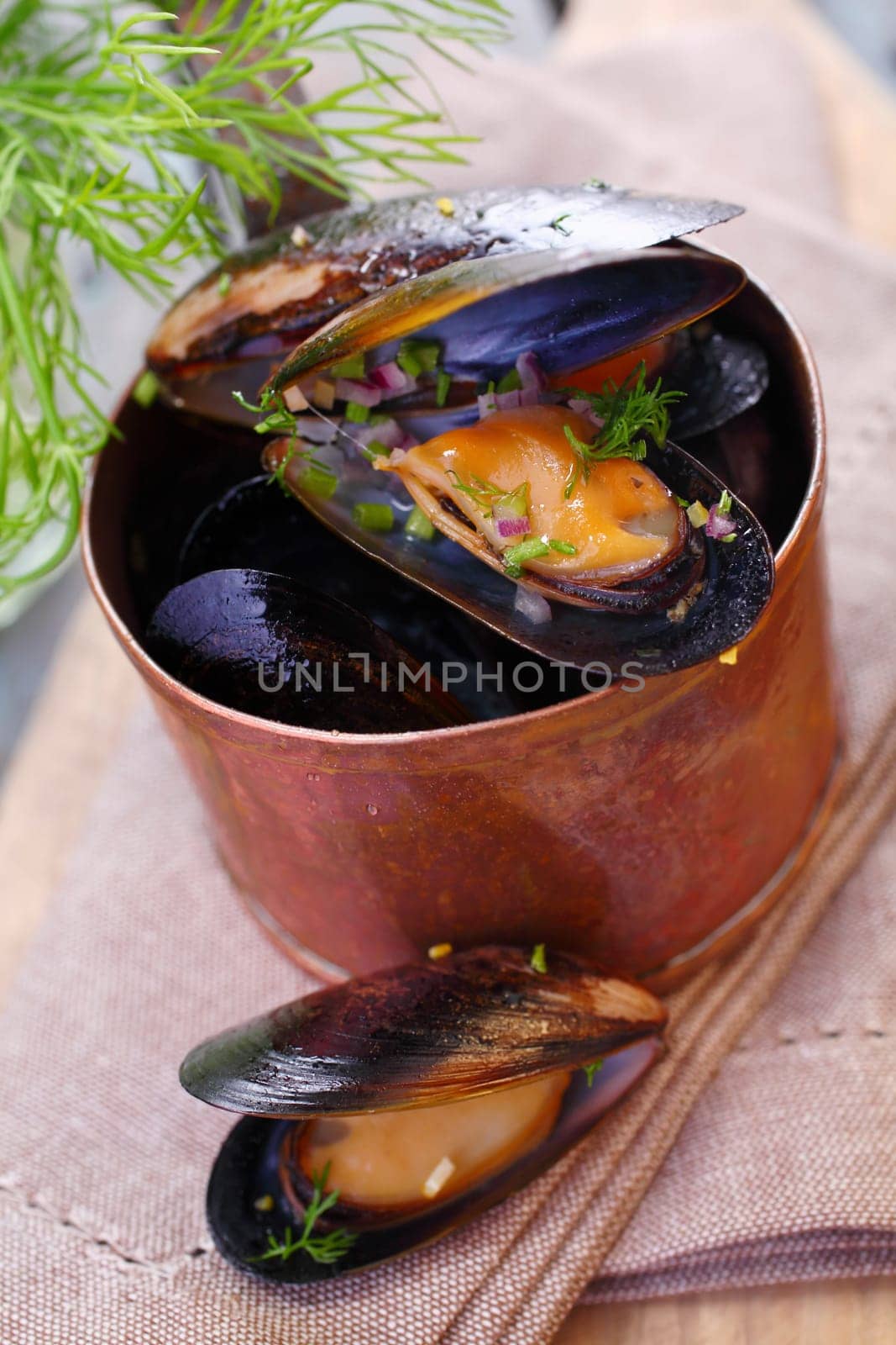 Steamed gourmet marine mussels in a copper pot seasoned with fresh dill for a delicious seafood appetizer
