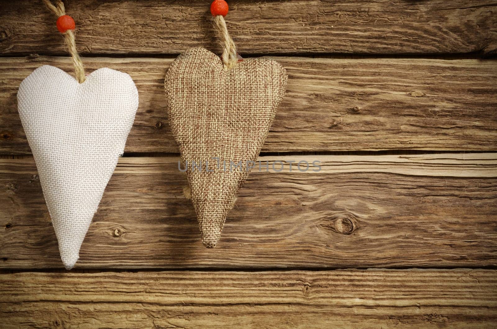 Christmas background for your sweetheart with two handmade rustic textile hearts in white and brown burlap on textured wooden boards with copyspace for your seasonal greeting