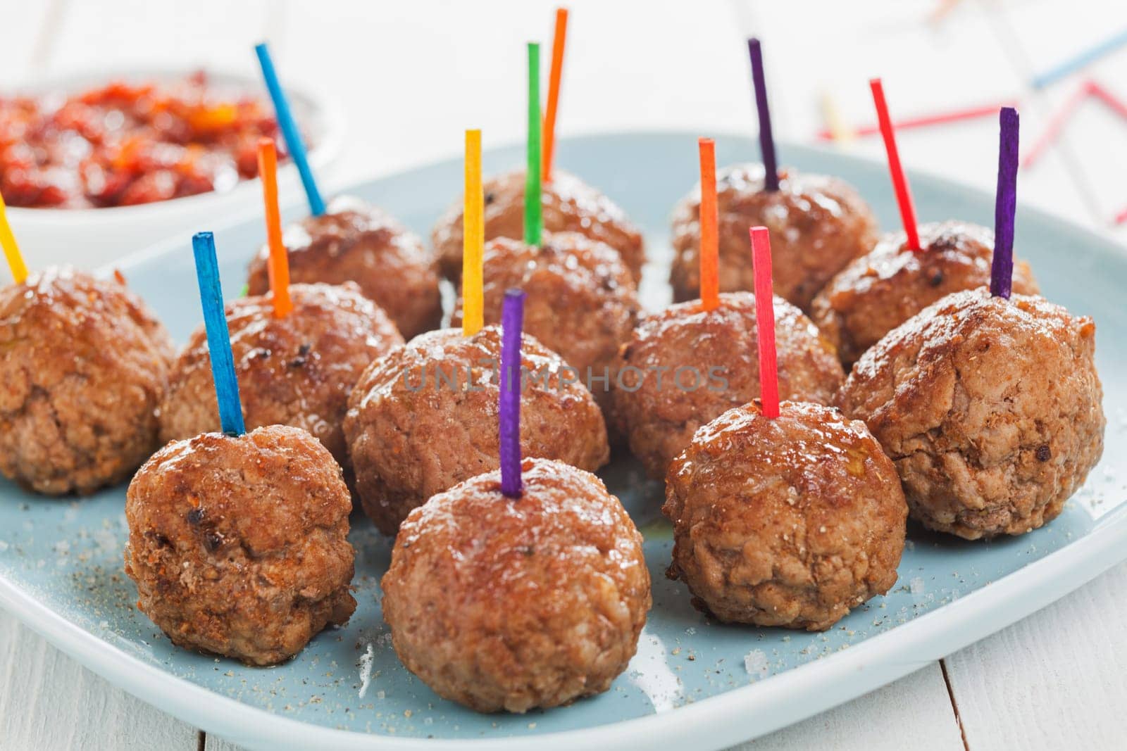 Tray of savory spicy meatballs for appetizers arranged on a tray on a buffet with colorful toothpicks to enable them to be dipped in sauce