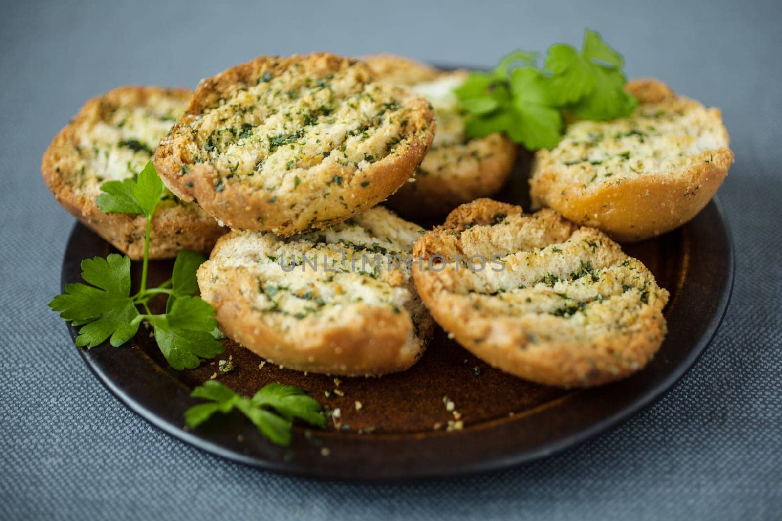 Plate of grilled or toasted crispy bread seasoned with fresh herbs to serve as an accompaniment to a meal