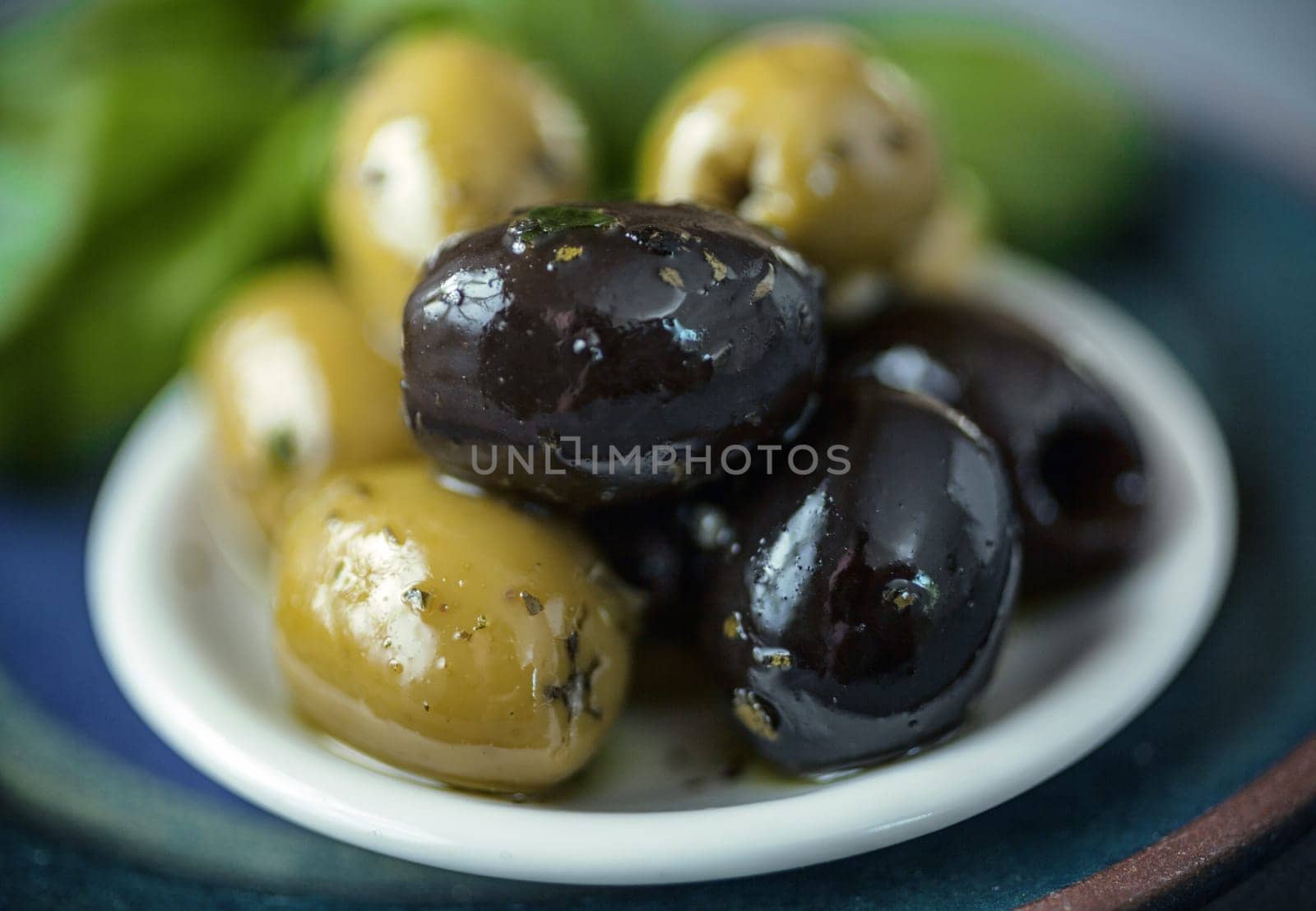Small bowl of cured fresh black and green olives served as snacks and appetizers with shallow dof