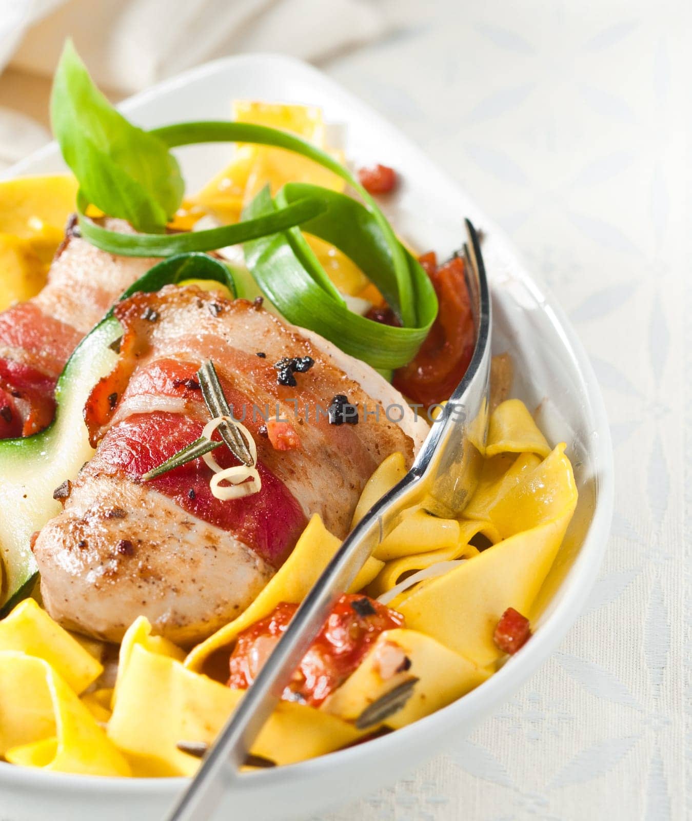 Pappardelle Italian noodles with bacon, tomato and fresh herbs seasoneed with pepper, close up high angle view