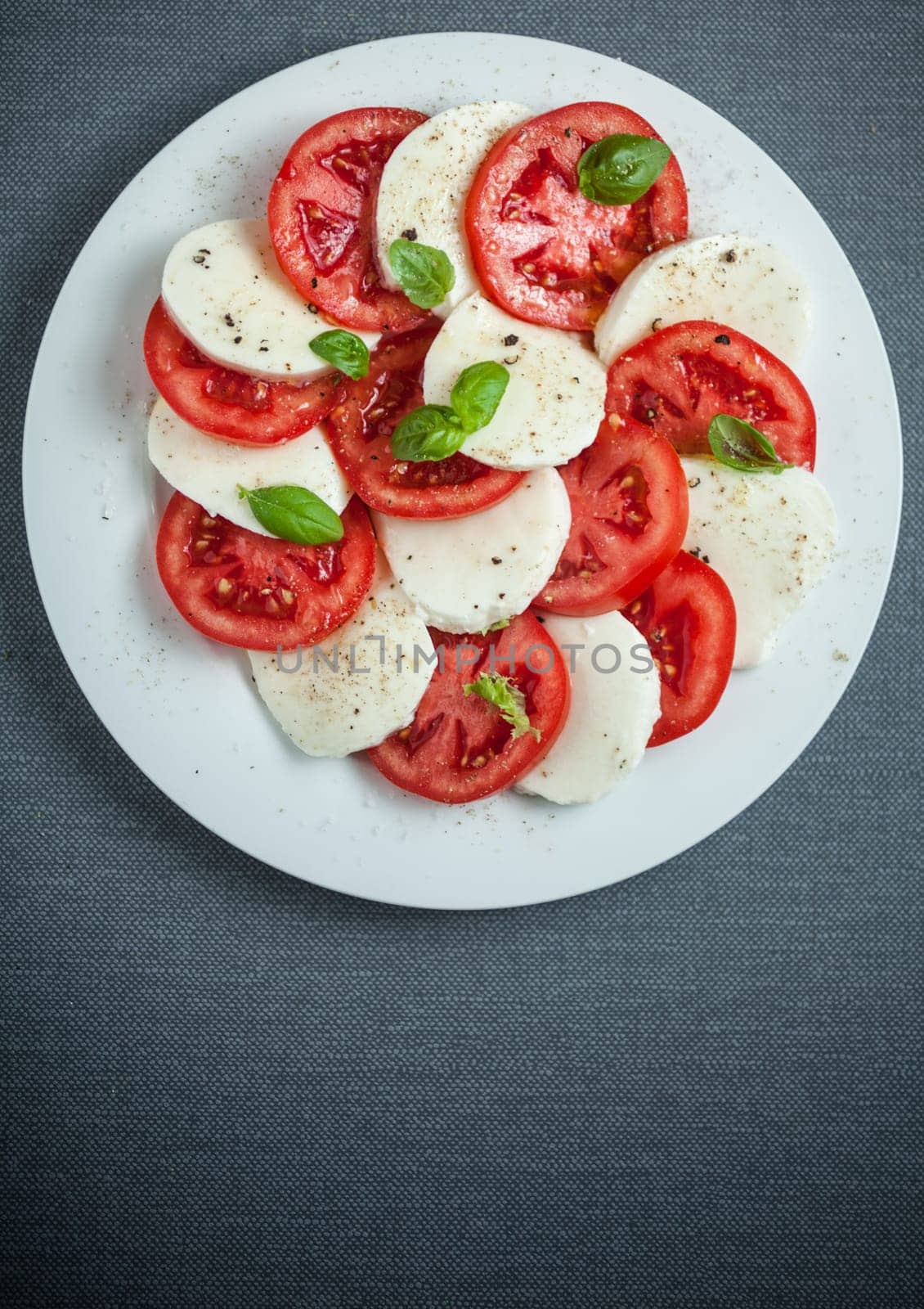 Italian Caprese salad viewed from above showing the colorful red and white pattern of alternating tomato and mozzarella cheese with fresh basil, with copyspace