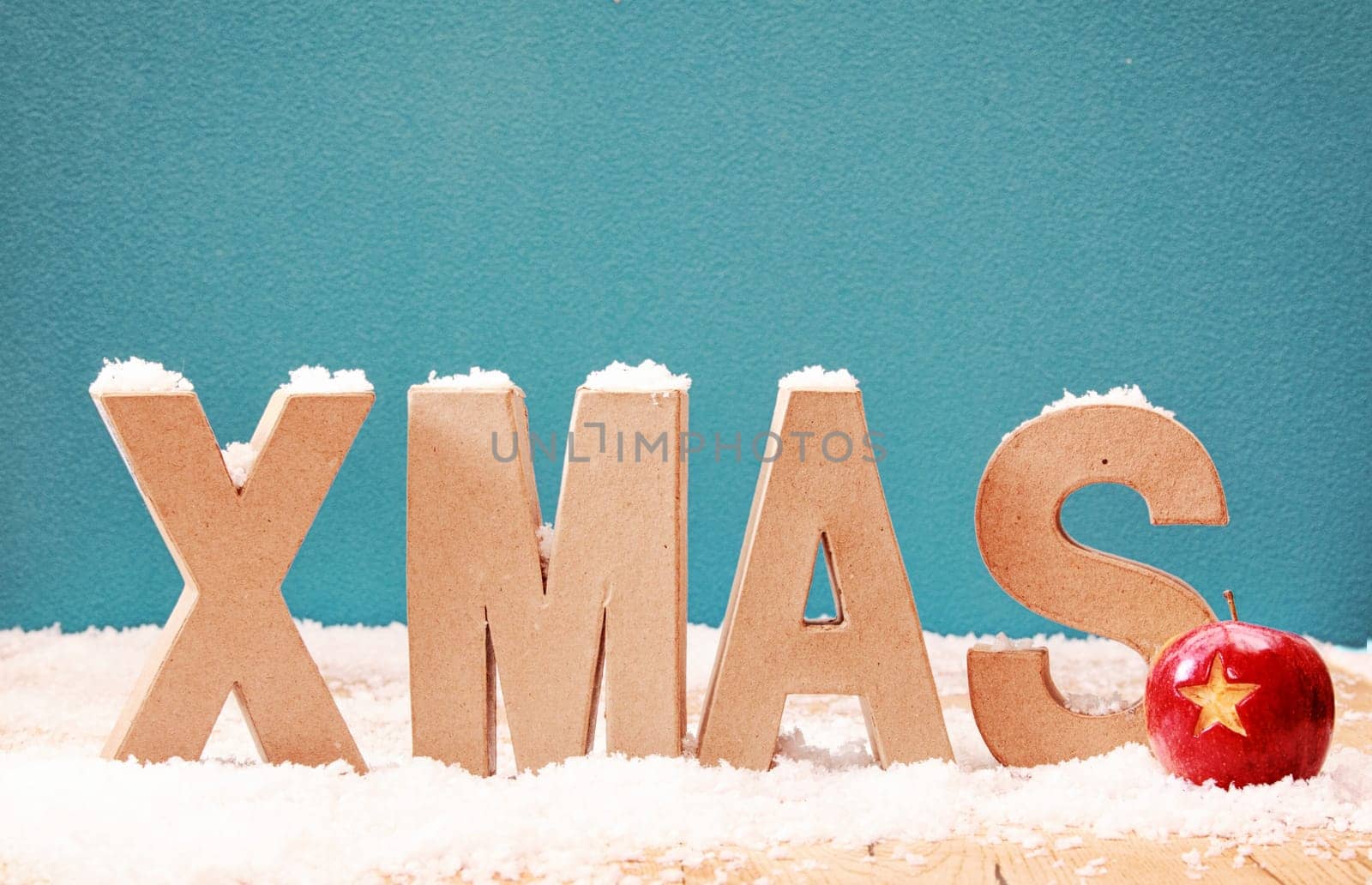 Xmas snow background with alphabet letters covered in a dusting of snow against a cool blue winter background with a colorful red bauble decorated with a star, copyspace for your Christmas message
