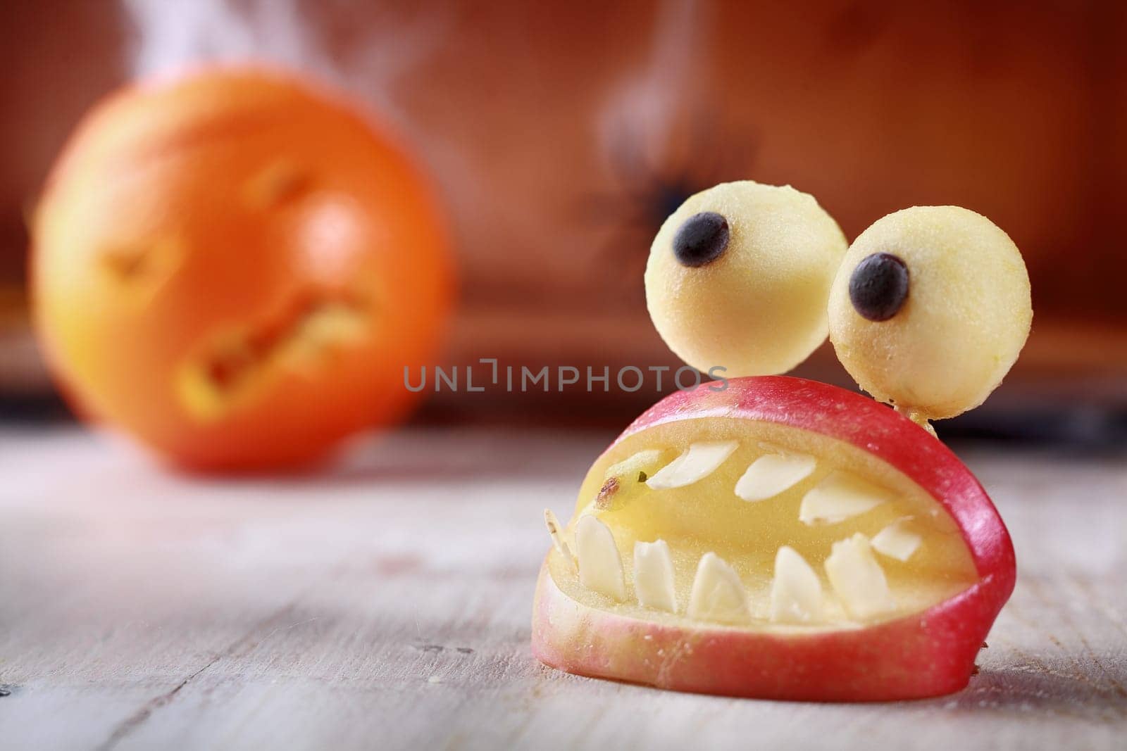 Fun scary homemade Halloween table decoration of fresh apple slices in the form of an open mouth with teeth topped by a pair of round googly dough eyes
