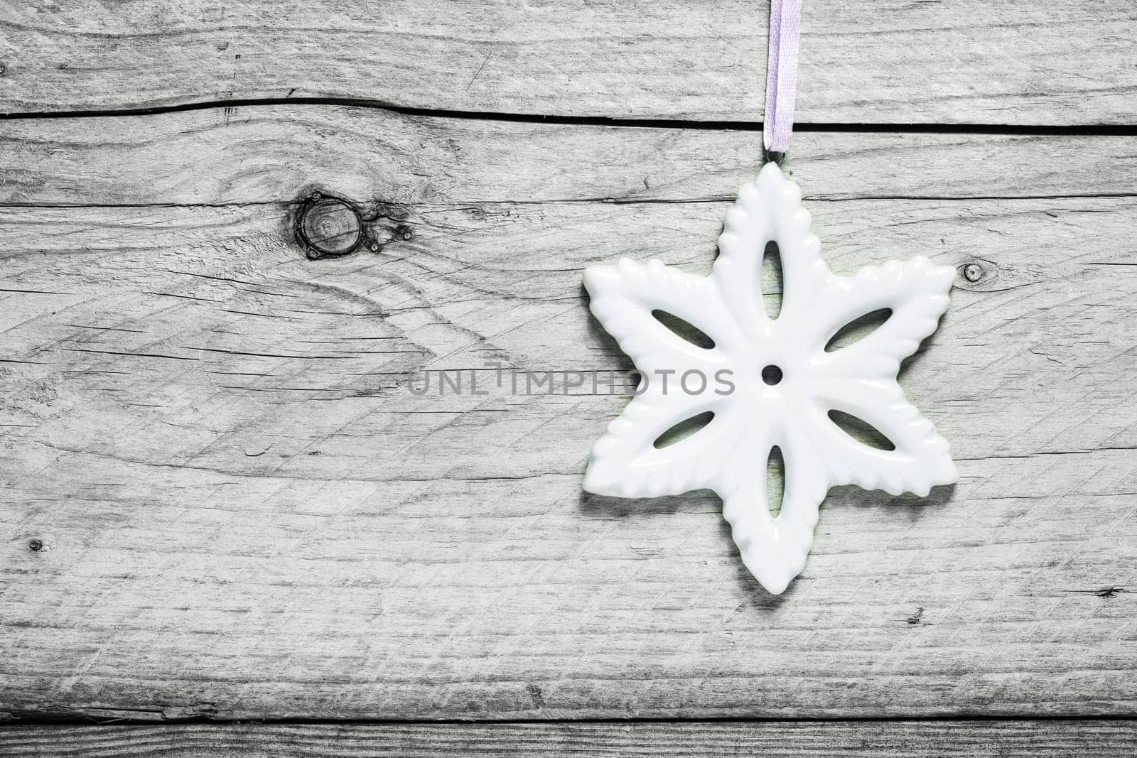 Christmas snowflake background with a white snowflake decoration hanging against old cracked wooden boards with copyspace for your Xmas message